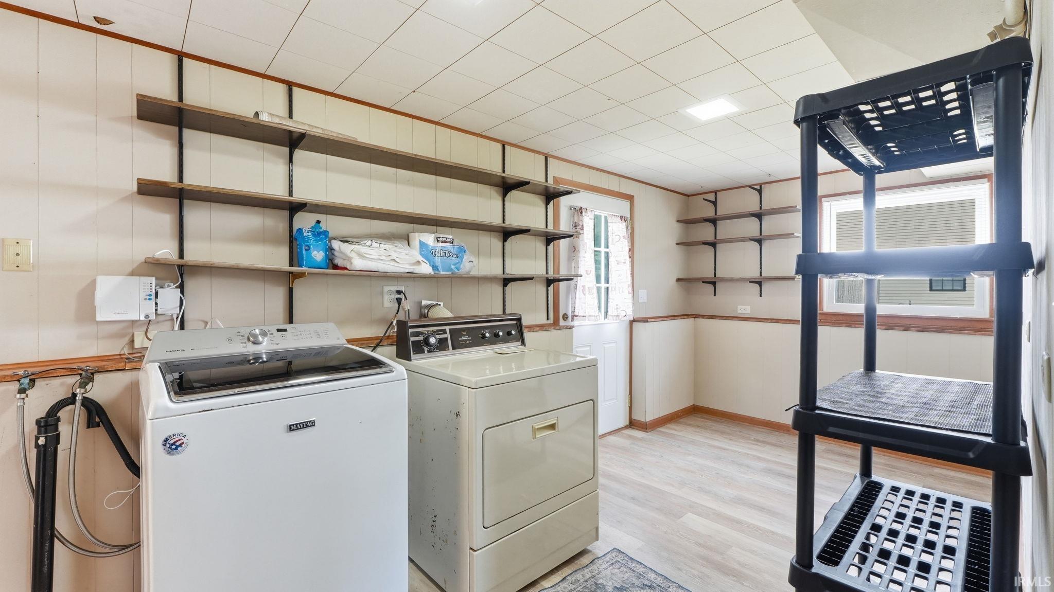 Dedicated laundry room featuring wood-finish flooring, an exterior door, and built-in wall shelving