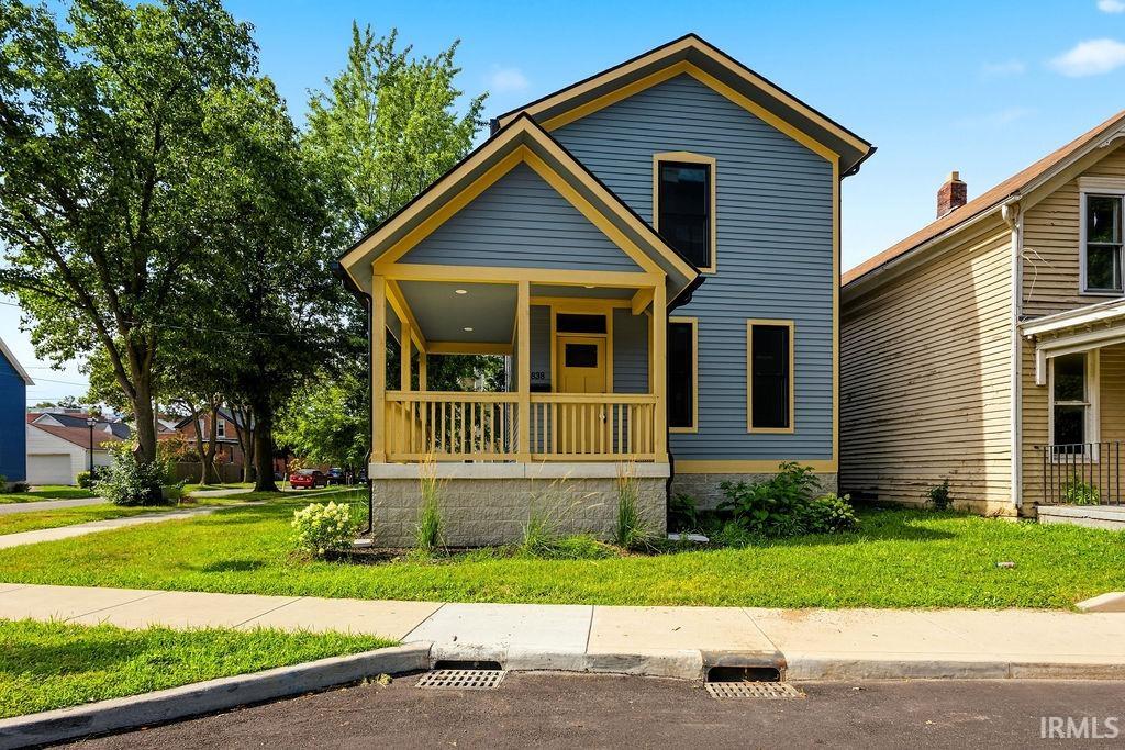 Two-story residence featuring blue horizontal siding with contrasting yellow trim, a covered front porch with yellow railings, and a prominent yellow entry door