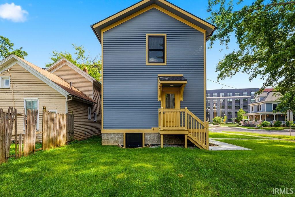 Rear exterior featuring blue siding, a vibrant yellow trim, and a newly constructed wood-finish deck and stairs