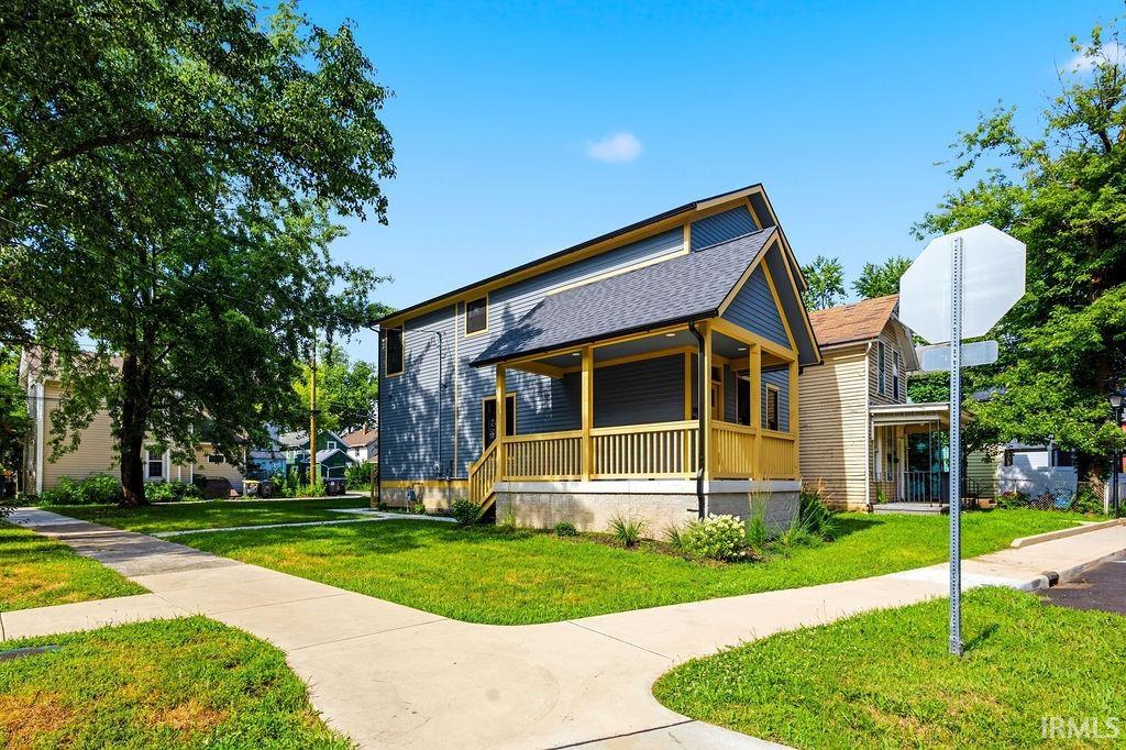 Modern bungalow featuring blue siding, a covered front porch with yellow railing, and an asphalt shingle roof