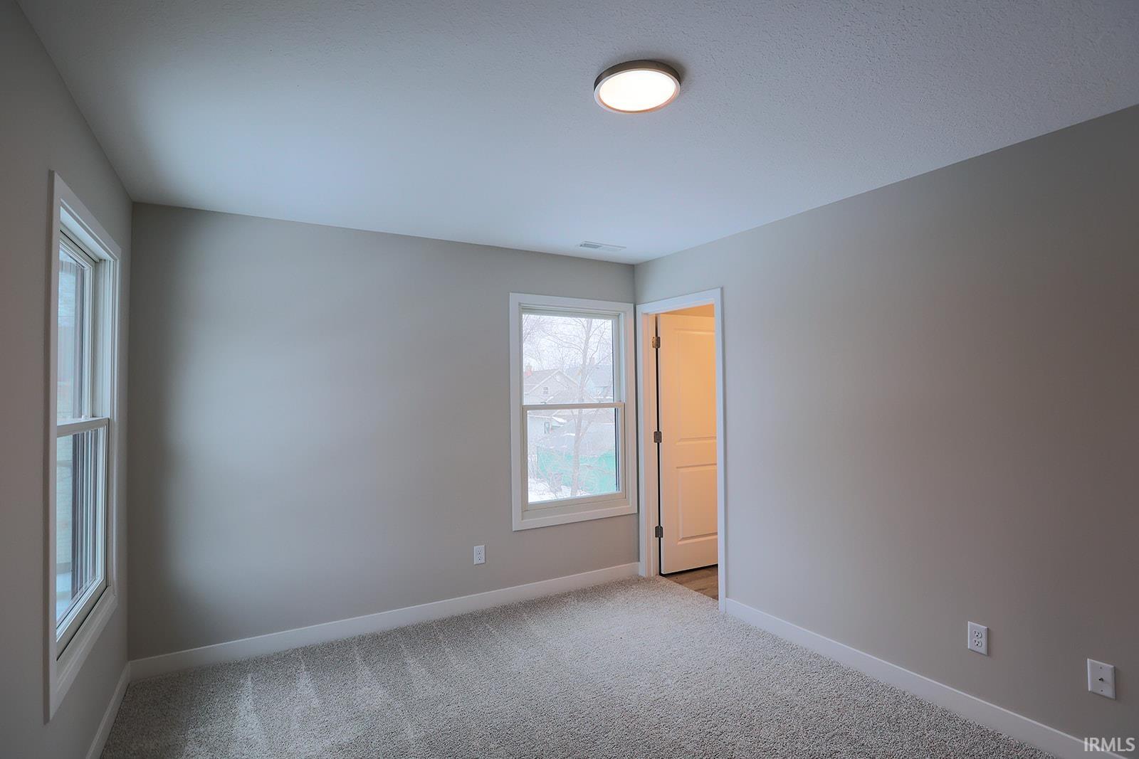 Carpeted spare room featuring baseboards