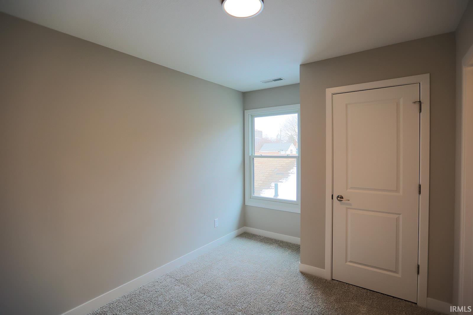 Unfurnished bedroom featuring light carpet and baseboards