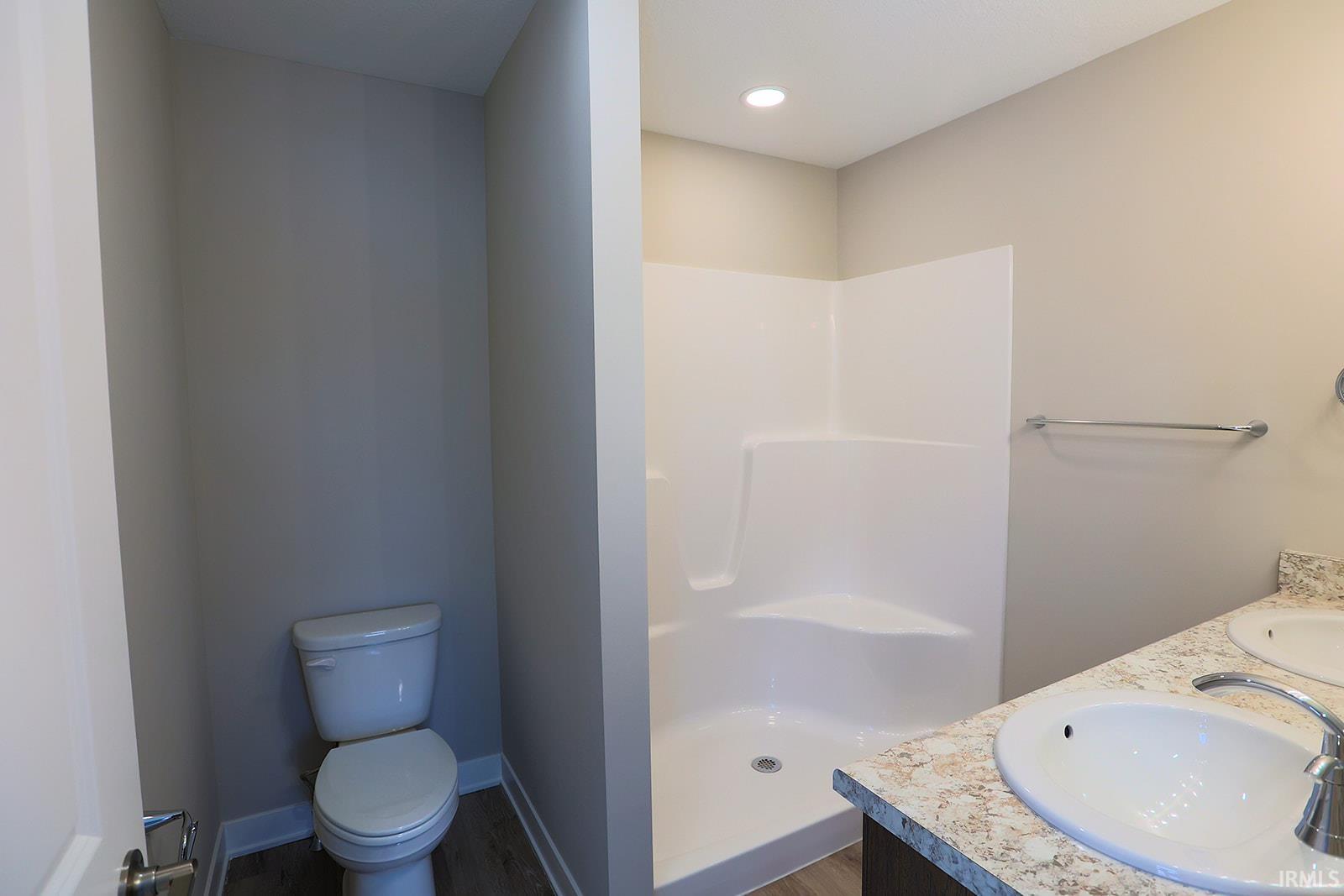 Full bathroom featuring double vanity, a shower stall, dark wood-type flooring, and recessed lighting