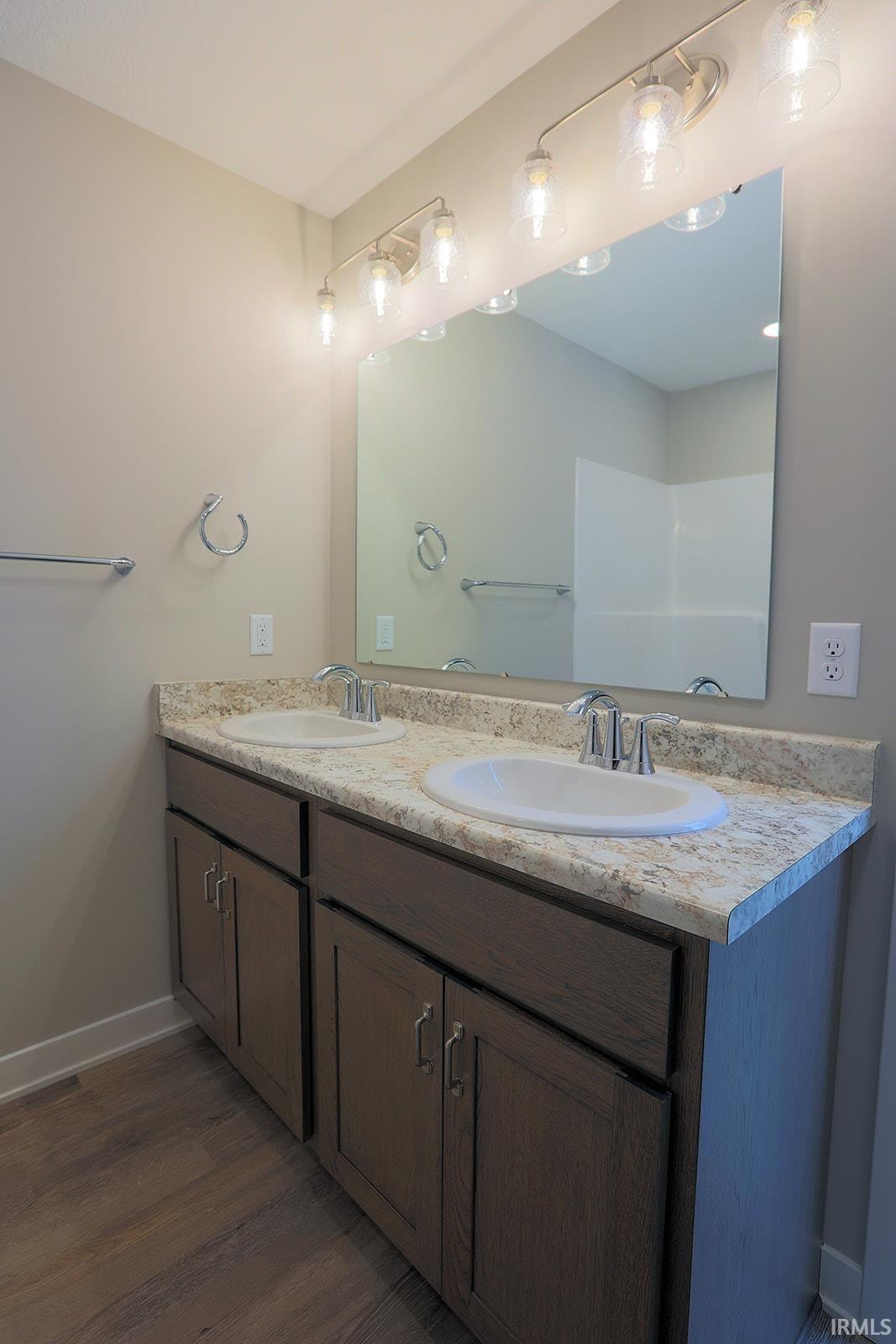 Bathroom featuring double vanity and dark wood finished floors