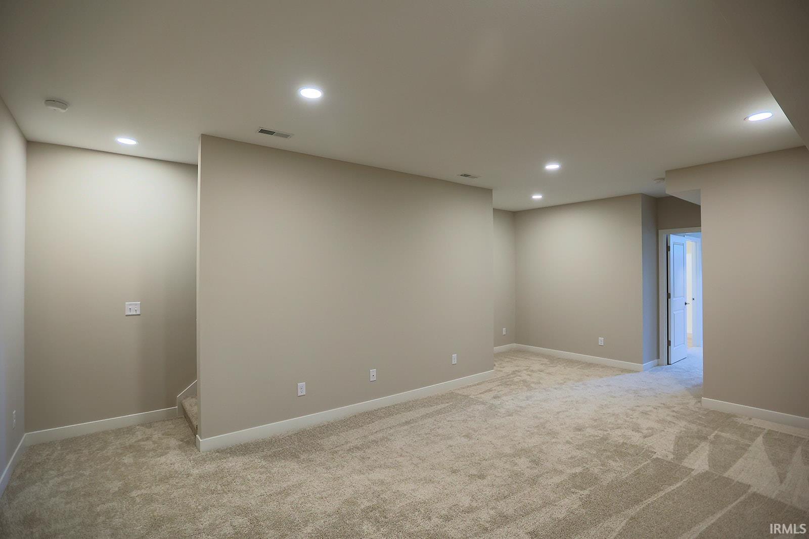 Empty room with recessed lighting and light colored carpet
