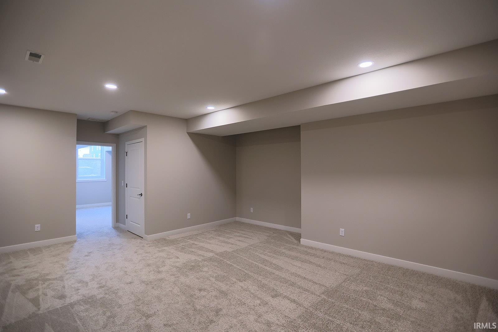 Below grade area with light colored carpet and recessed lighting
