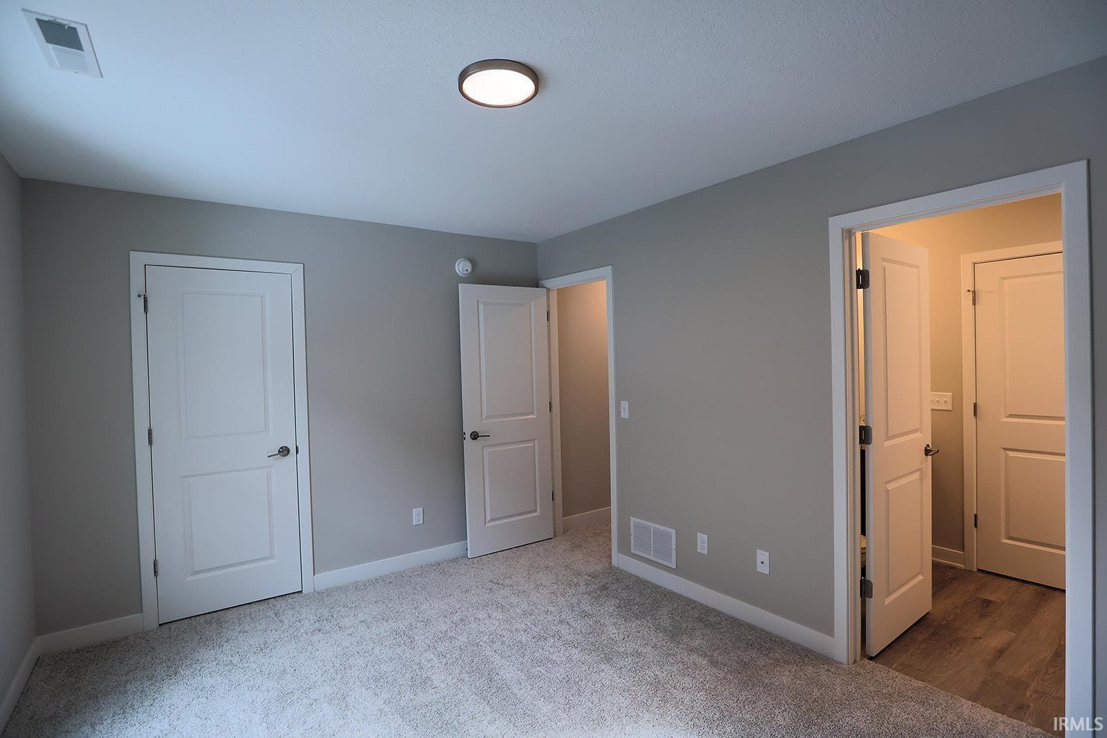 Unfurnished bedroom featuring light carpet and baseboards