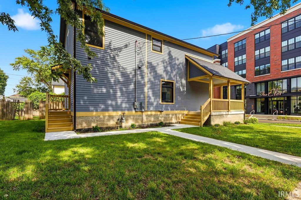 Two-story exterior featuring horizontal siding, a covered porch with wood railings, and a side deck with wooden steps