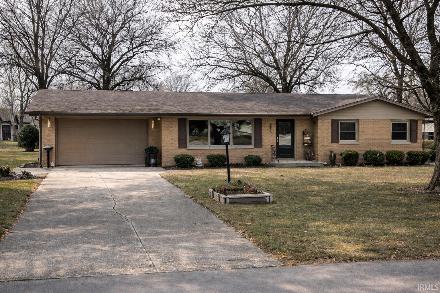 Ranch-style house with an attached garage, driveway, a front lawn, and brick siding