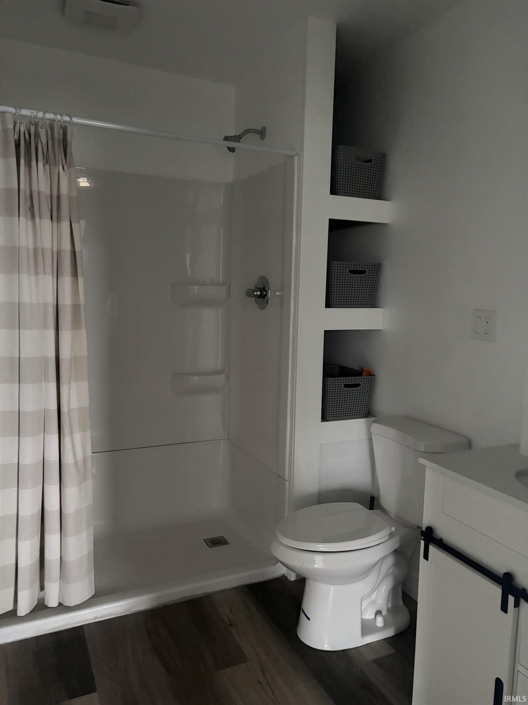 Bathroom with a shower stall, dark wood-type flooring, and vanity