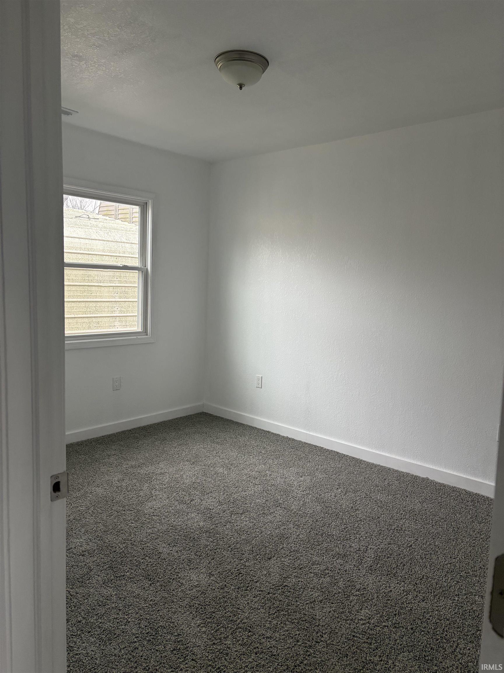 Carpeted empty room featuring baseboards