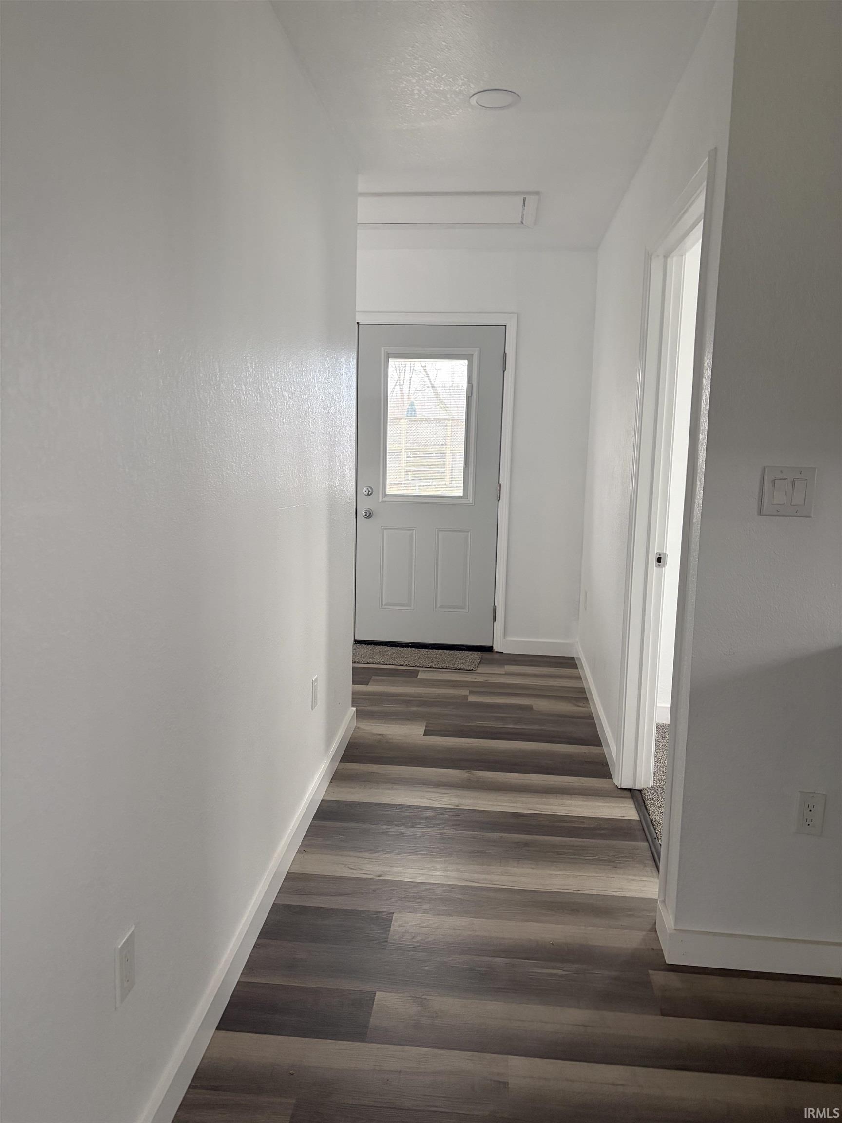 Corridor featuring dark wood-style flooring and baseboards