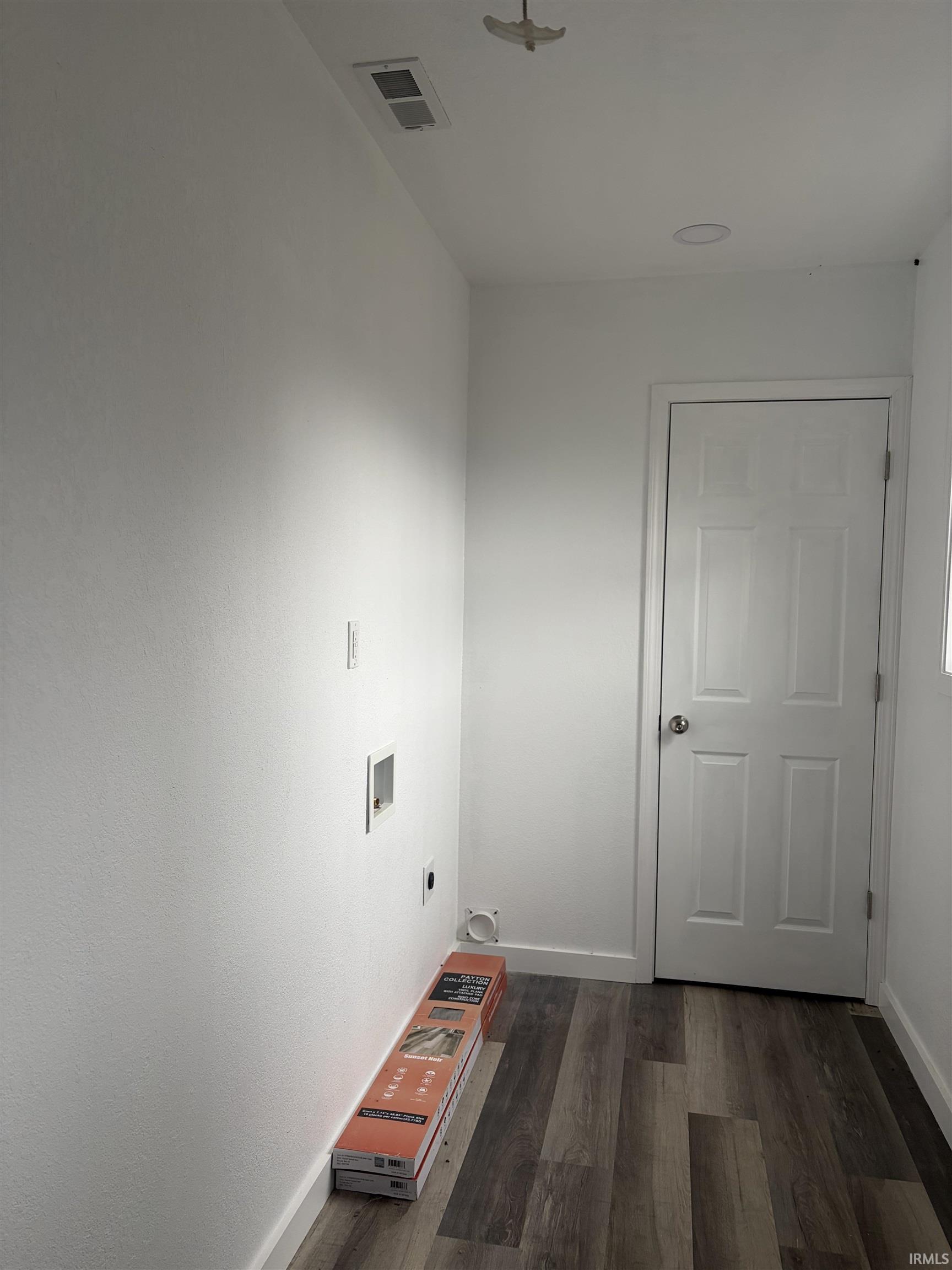 Washroom with dark wood-style flooring and hookup for a washing machine