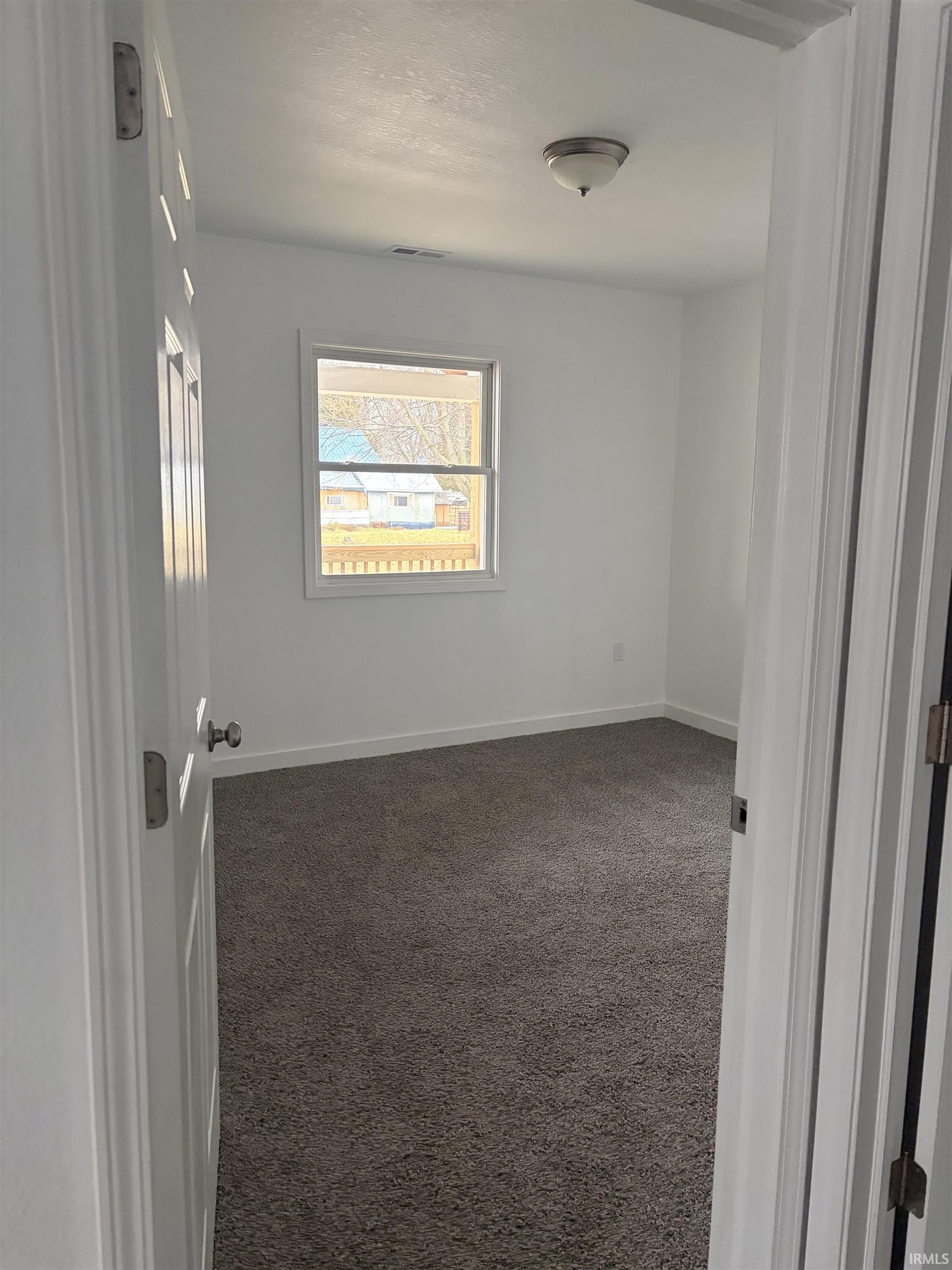 Spare room with dark colored carpet and baseboards