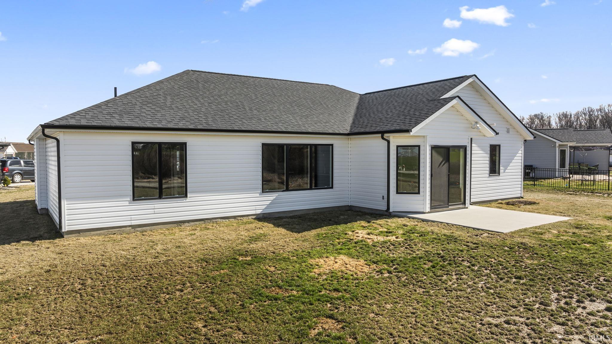 Back of house with roof with shingles, a patio area, and a lawn