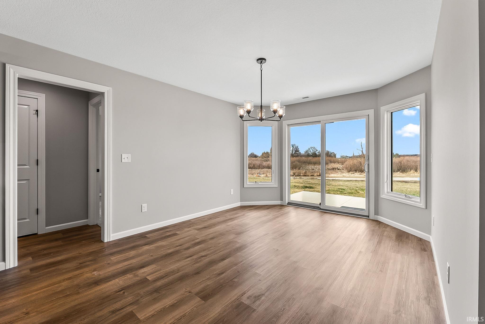 Unfurnished dining area featuring a chandelier and dark wood finished floors