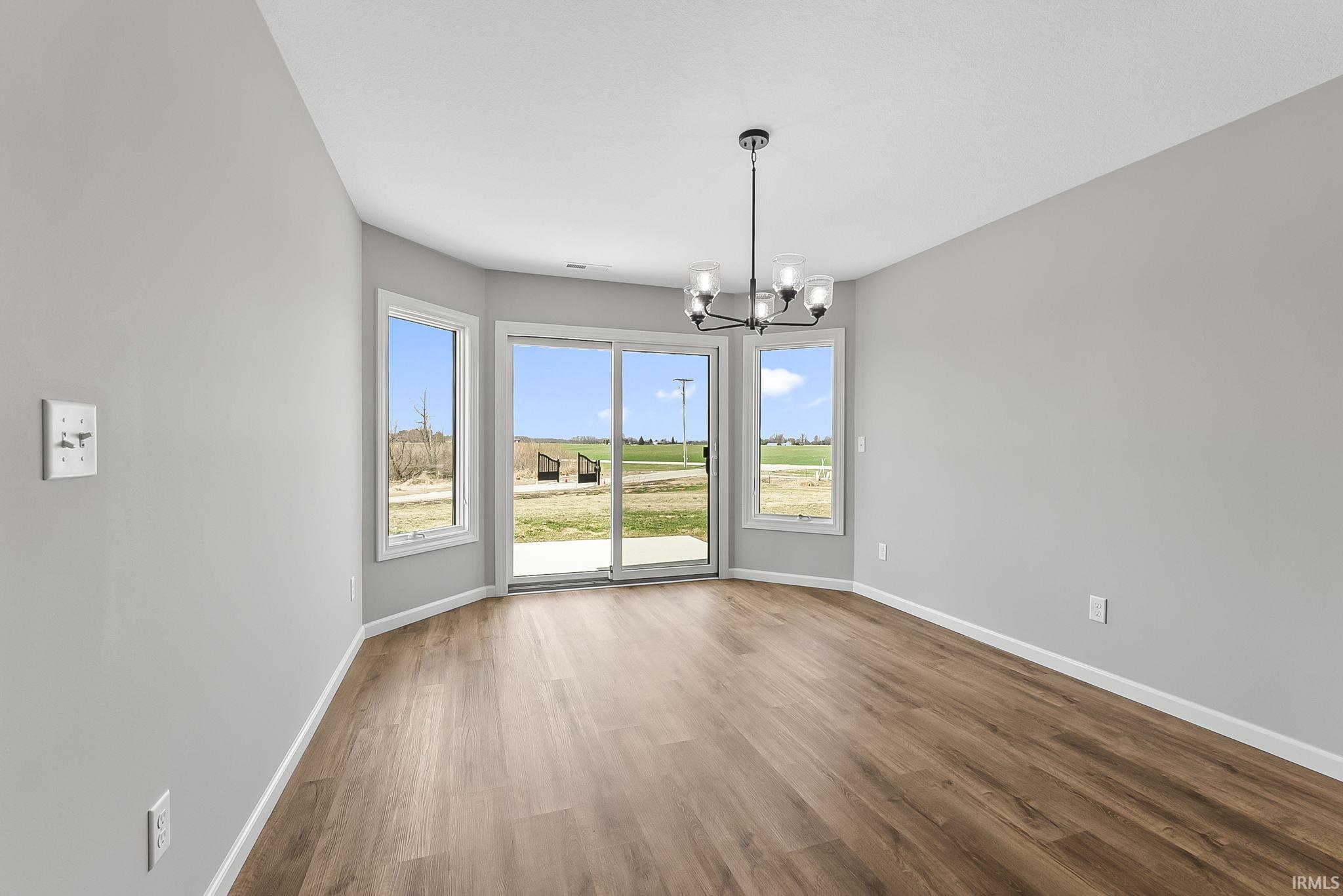 Unfurnished dining area with hanging lights and wood finished floors