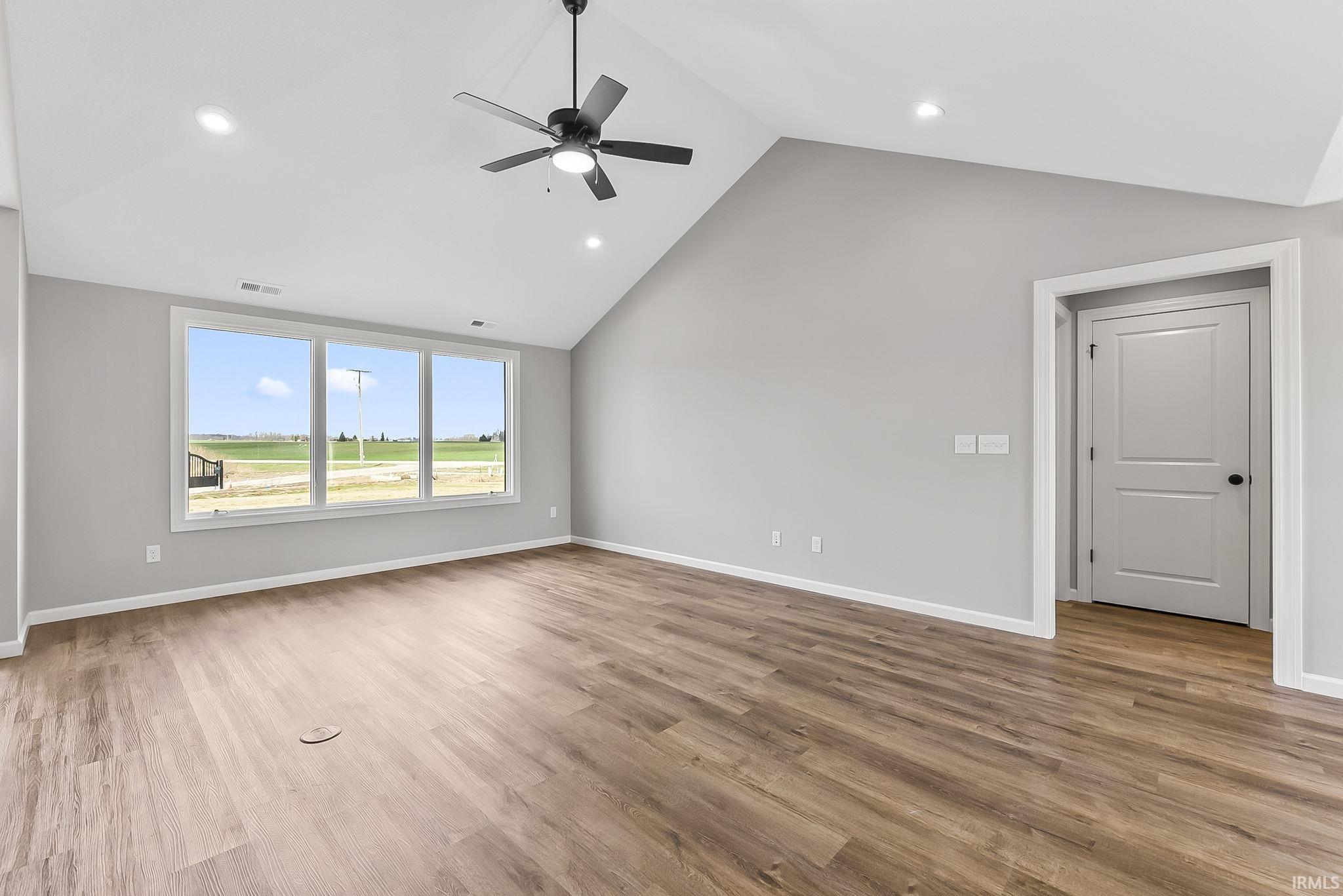 Unfurnished living room featuring a ceiling fan, a high ceiling, recessed lighting, and light wood-type flooring
