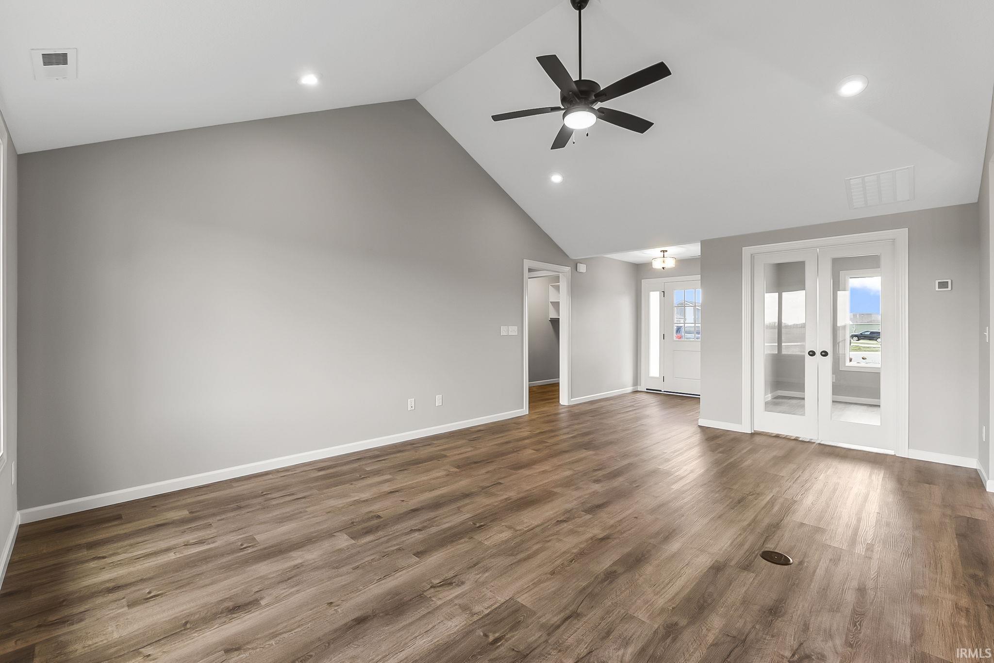 Unfurnished living room with a high ceiling, recessed lighting, a ceiling fan, dark wood finished floors, and french doors