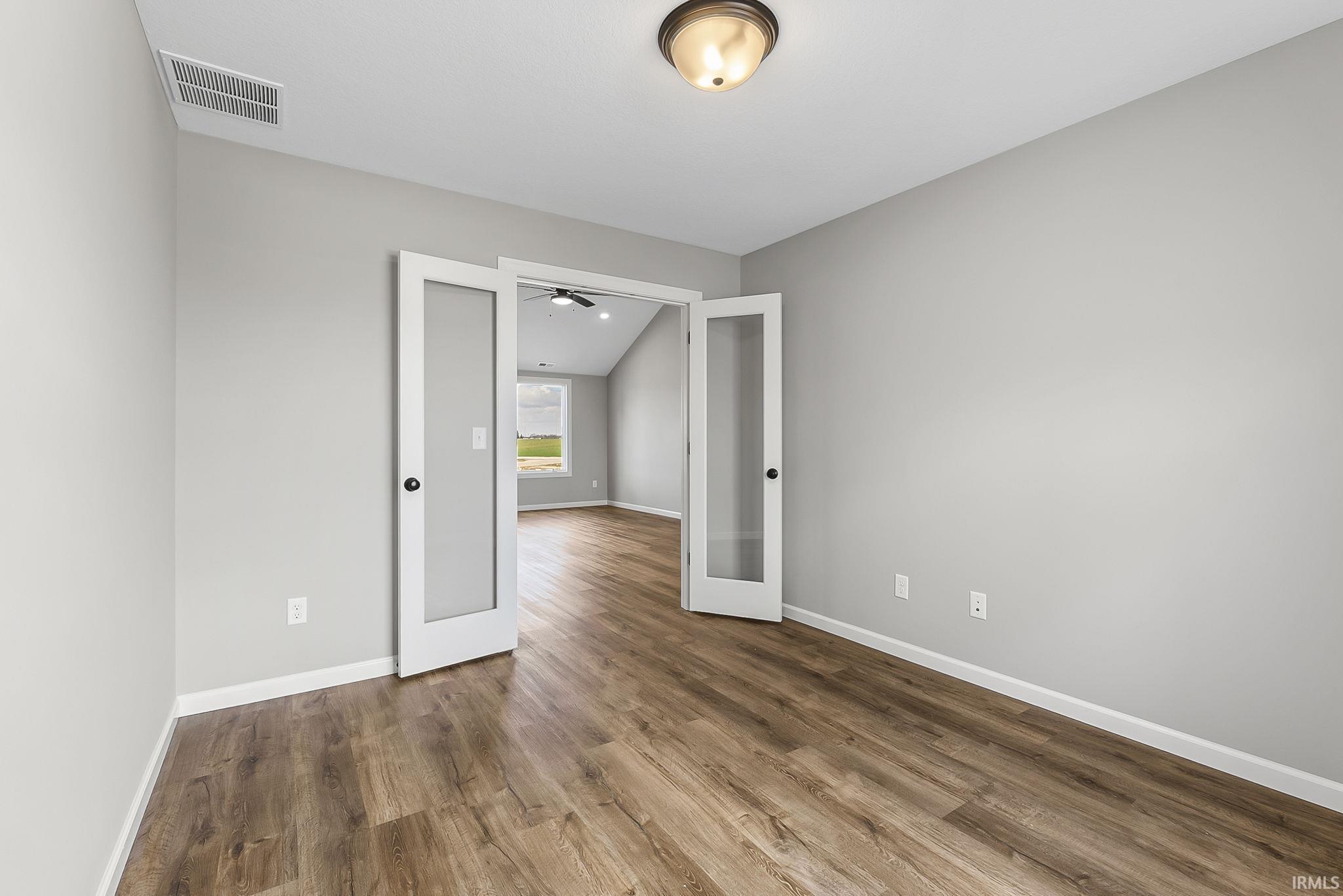 Spare room featuring french doors, dark wood-type flooring, and ceiling fan