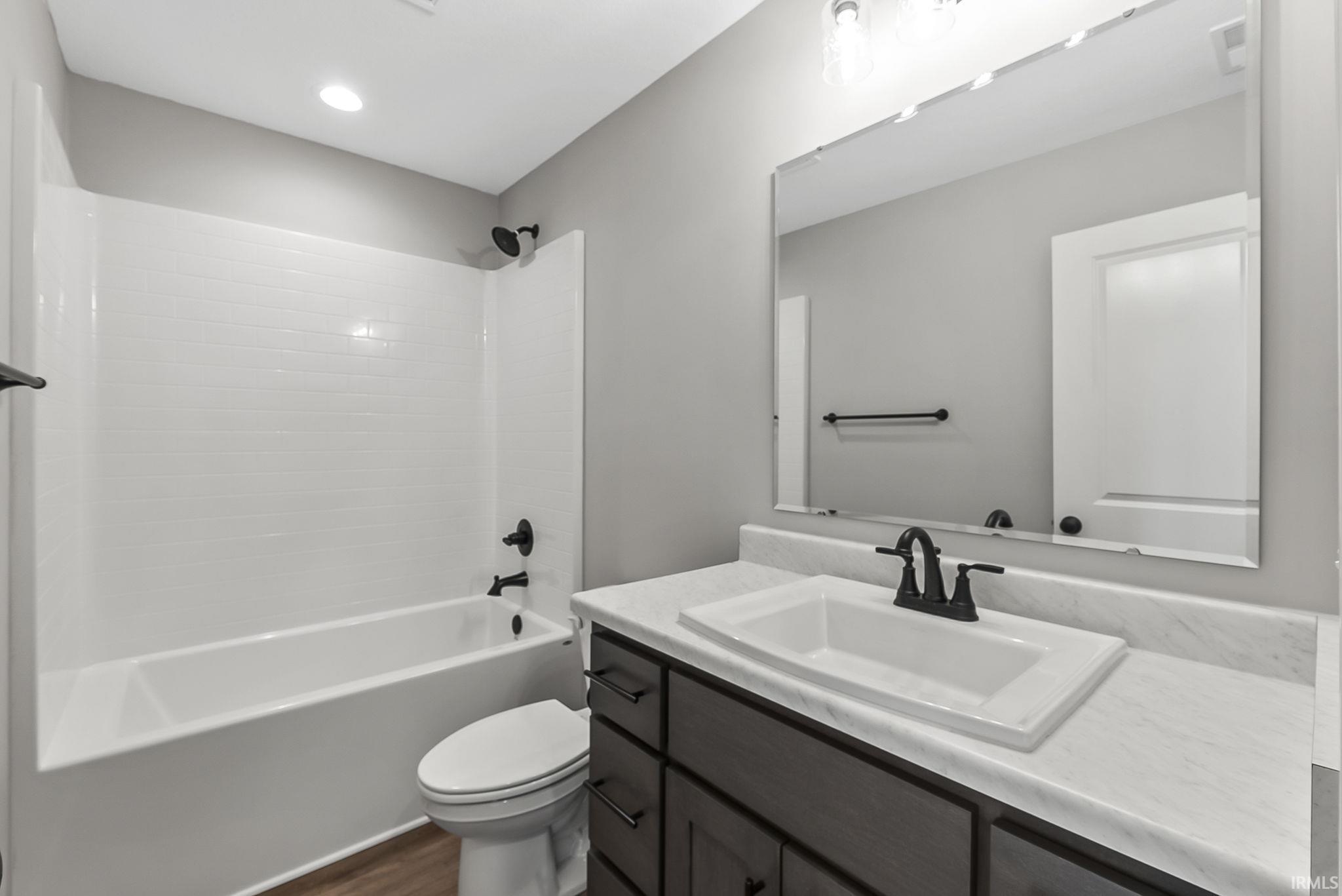 Full bathroom featuring vanity, bathing tub / shower combination, and dark wood-type flooring