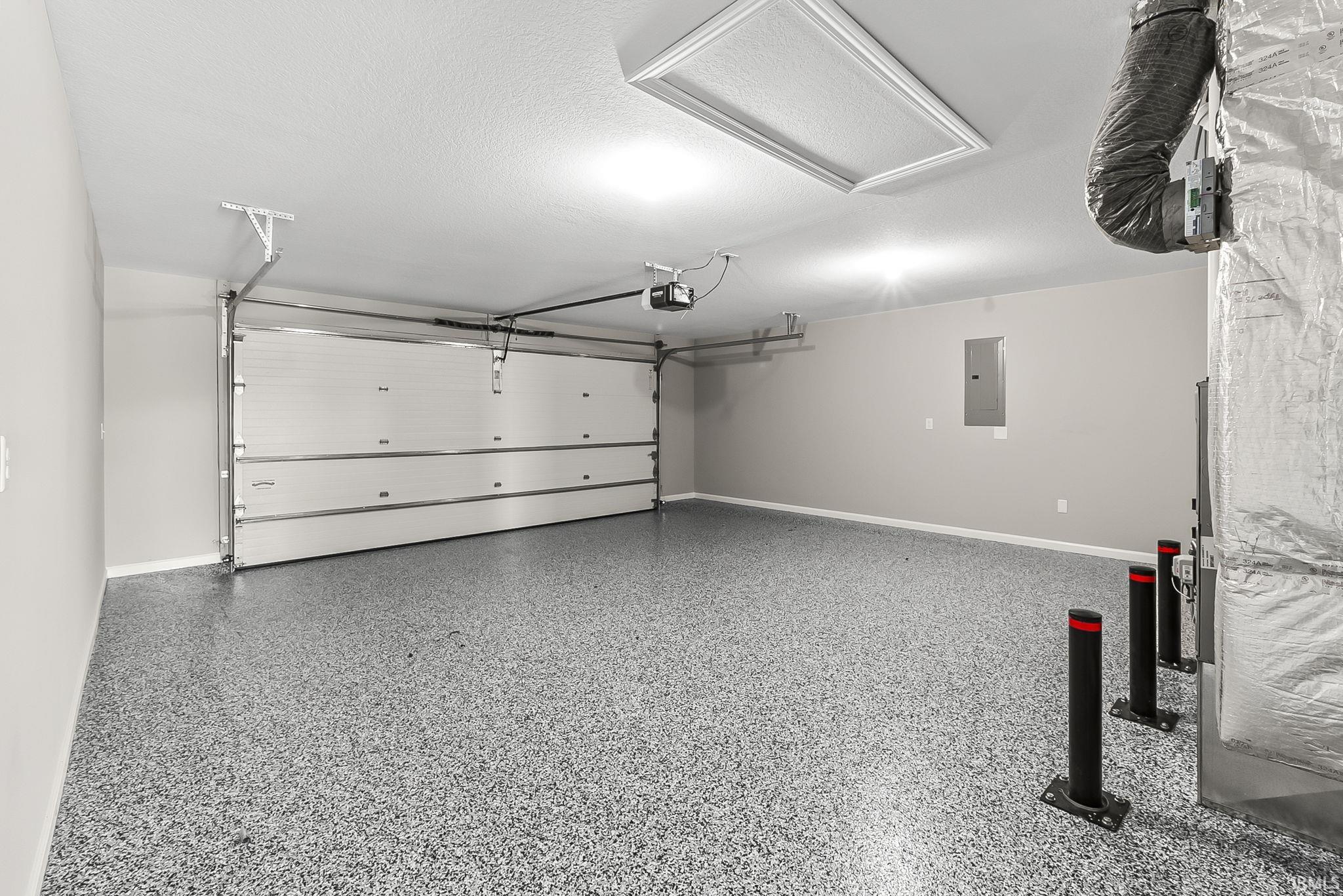 Garage featuring electric panel and baseboards