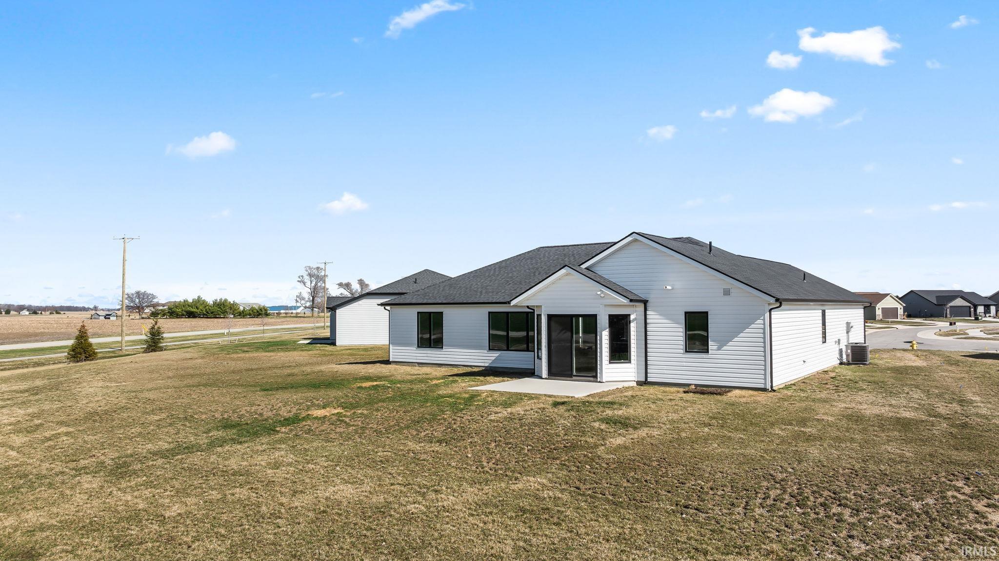 Back of house with a lawn, a patio, and roof with shingles