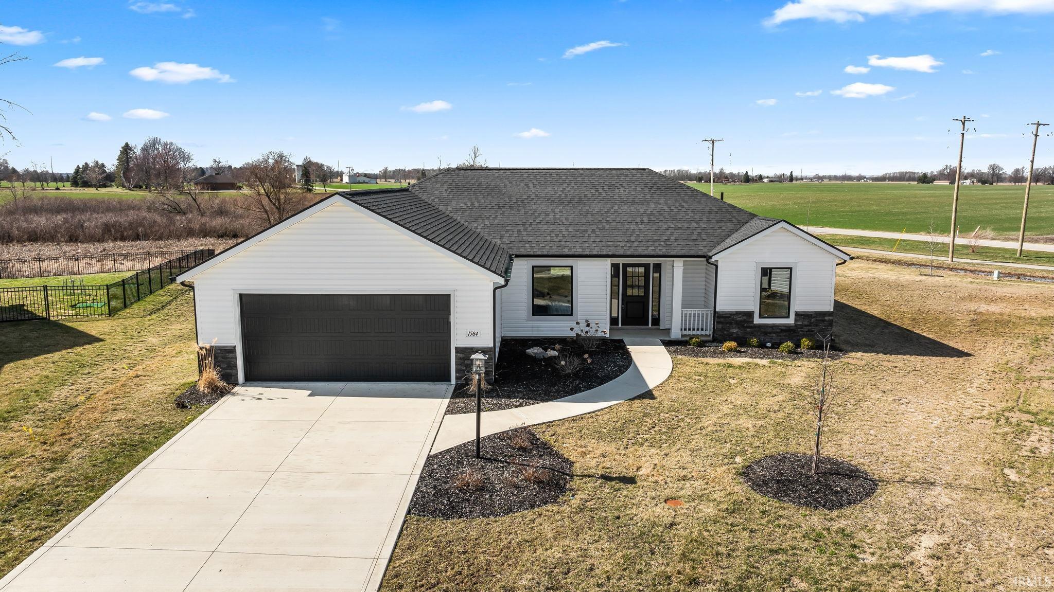 Modern farmhouse featuring a shingled roof, driveway, a garage, and stone siding