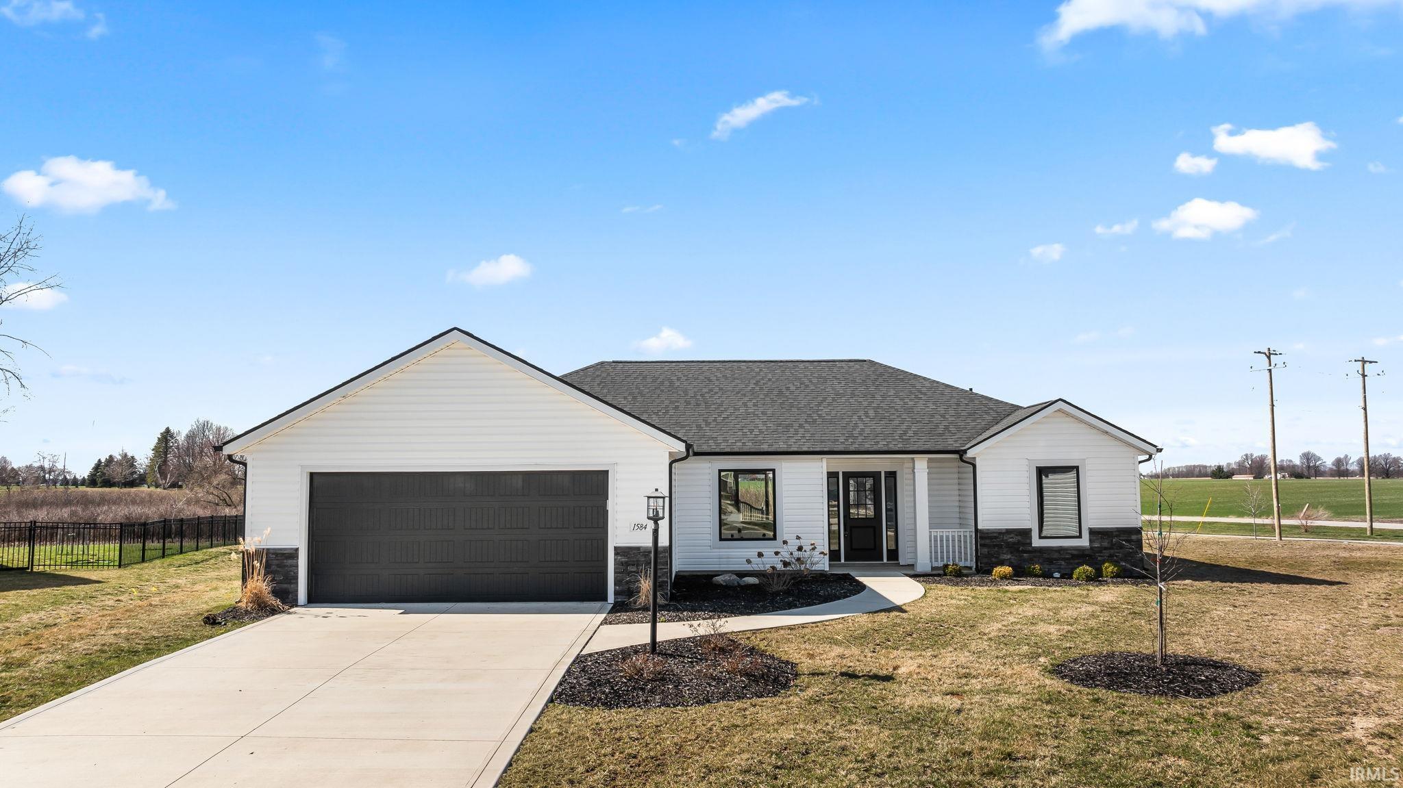 View of front facade with stone siding, an attached garage, driveway, and roof with shingles