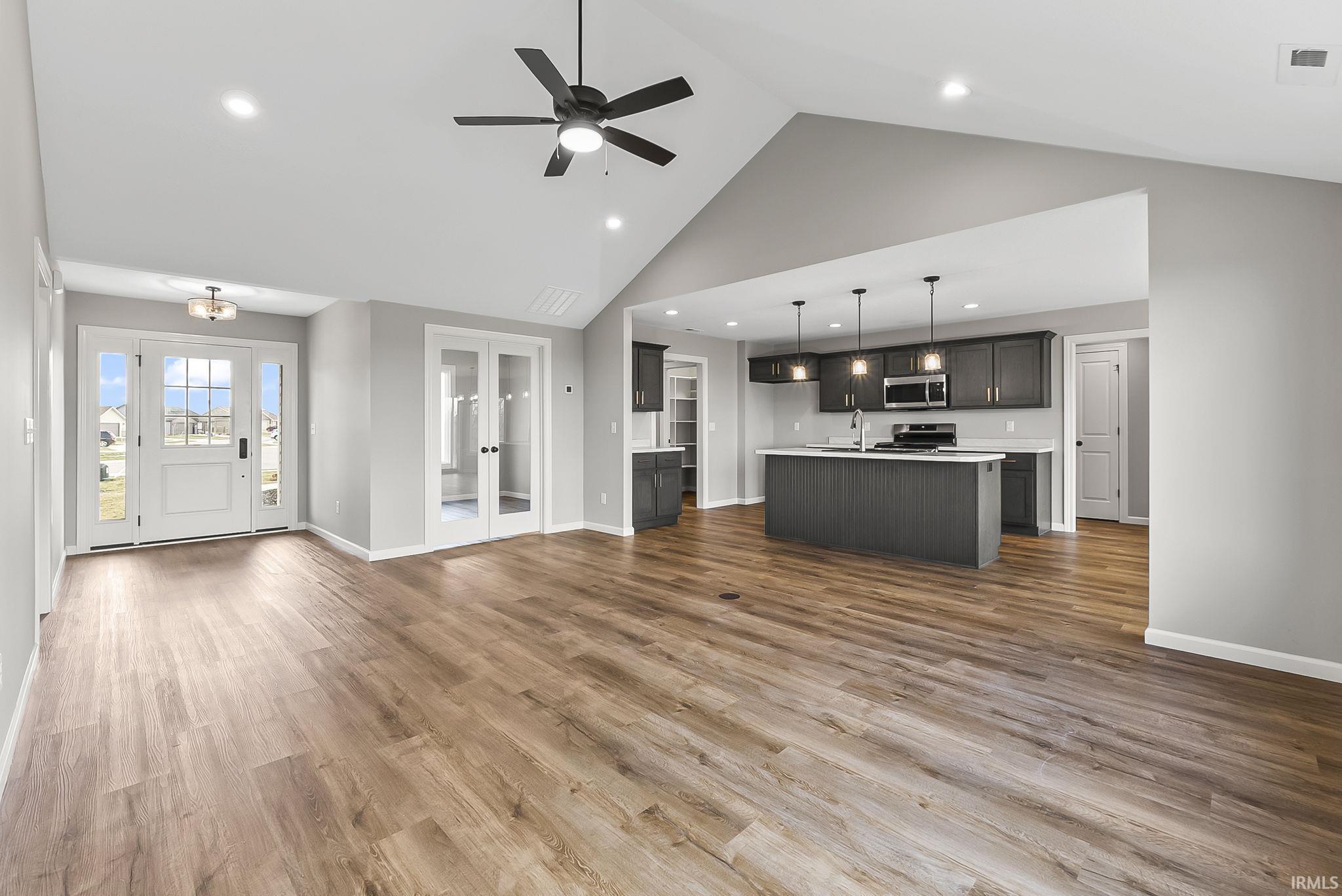 Unfurnished living room with a ceiling fan, a high ceiling, recessed lighting, and dark wood-style floors