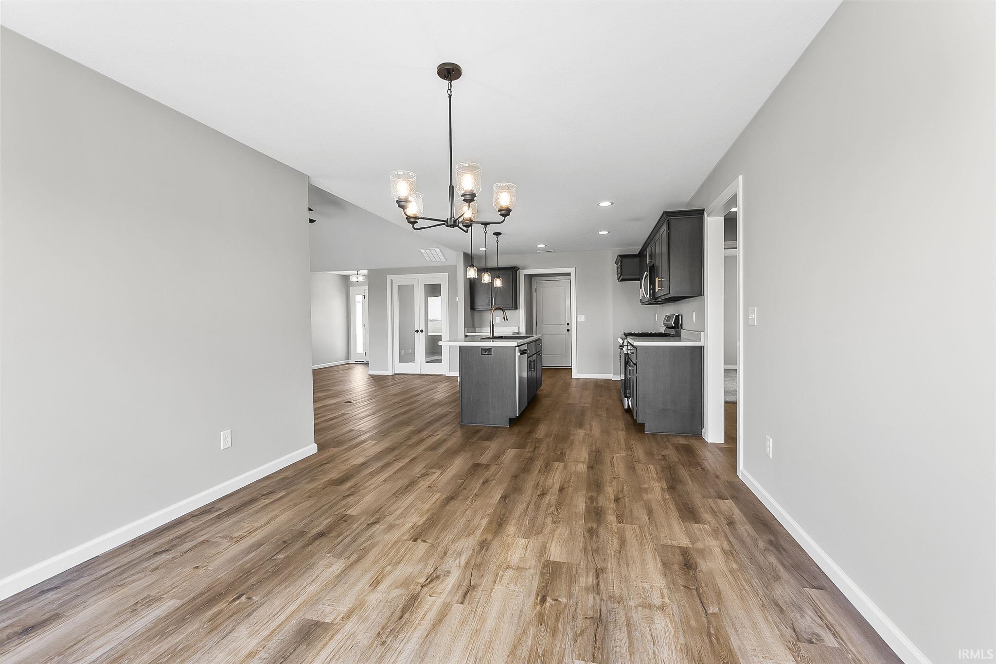 Kitchen with a center island, suspended lighting, open floor plan, dark wood-style floors, and light countertops