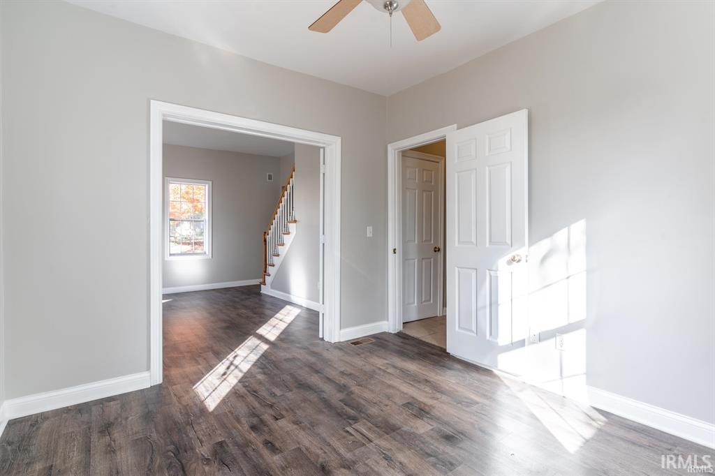 Empty room featuring dark wood-type flooring and a ceiling fan