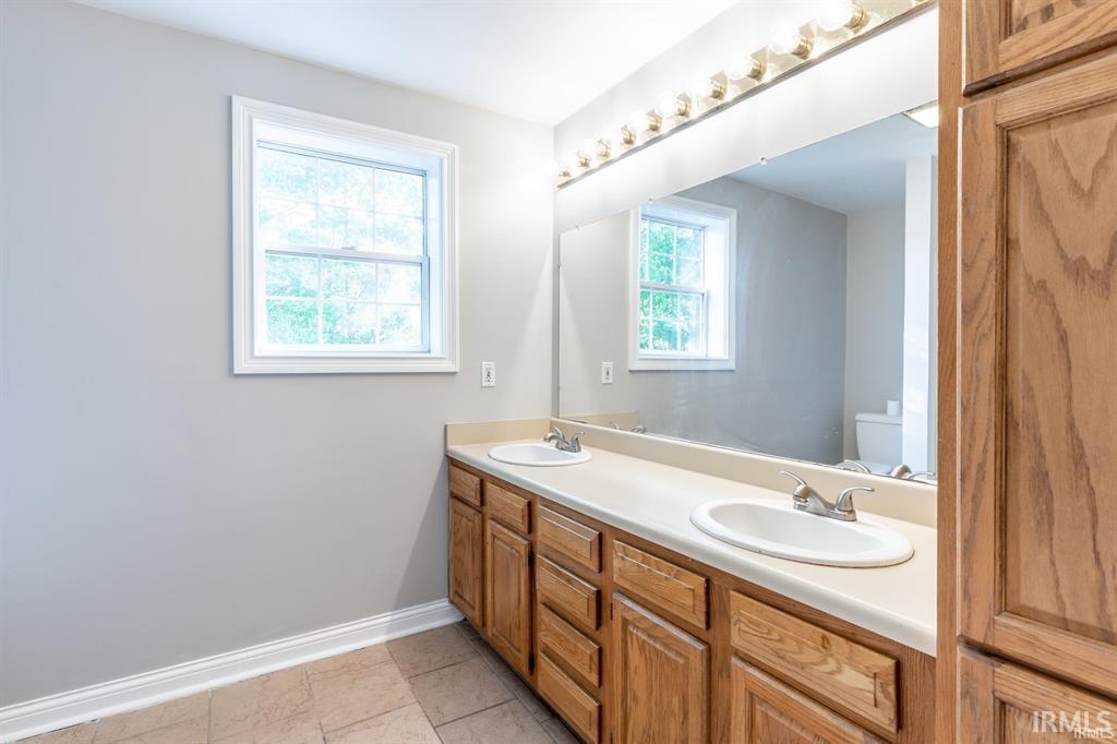 Full bathroom featuring double vanity and baseboards