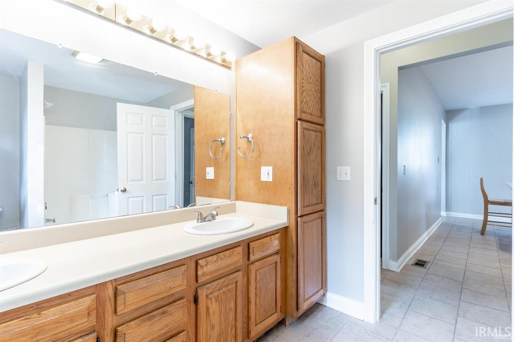 Full bathroom with double vanity and baseboards