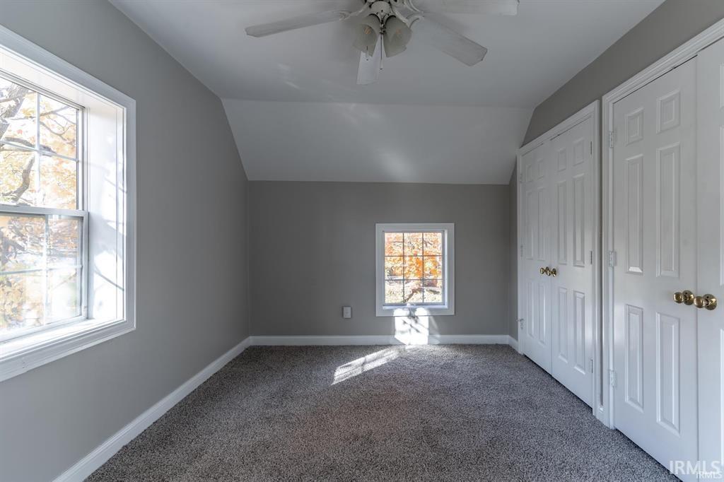Bonus room with vaulted ceiling, ceiling fan, and carpet