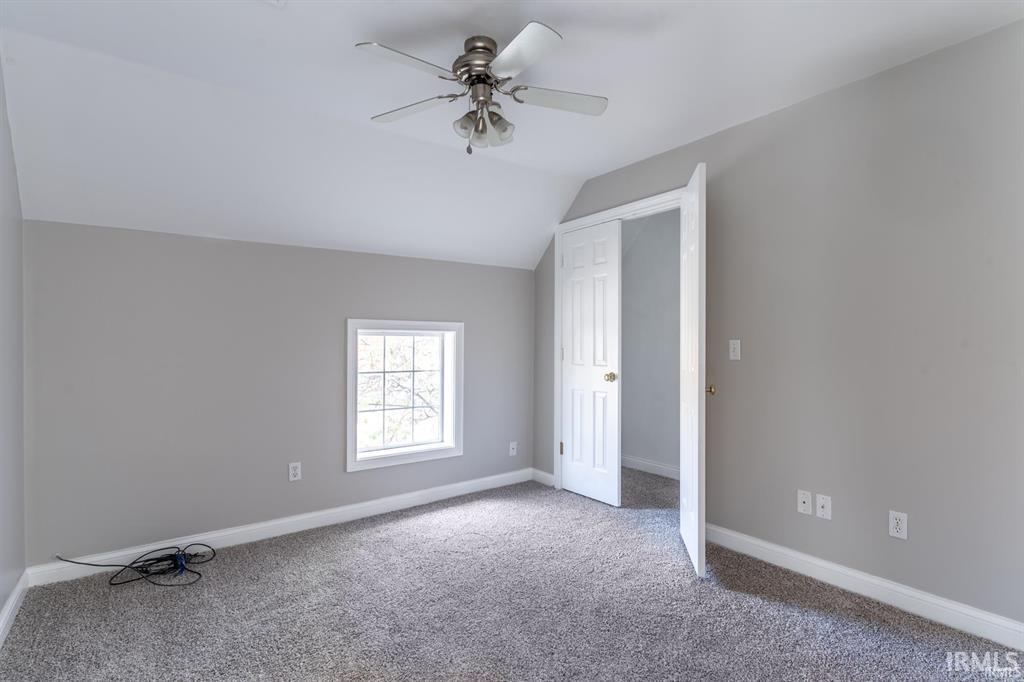 Bonus room with vaulted ceiling, a ceiling fan, and light colored carpet