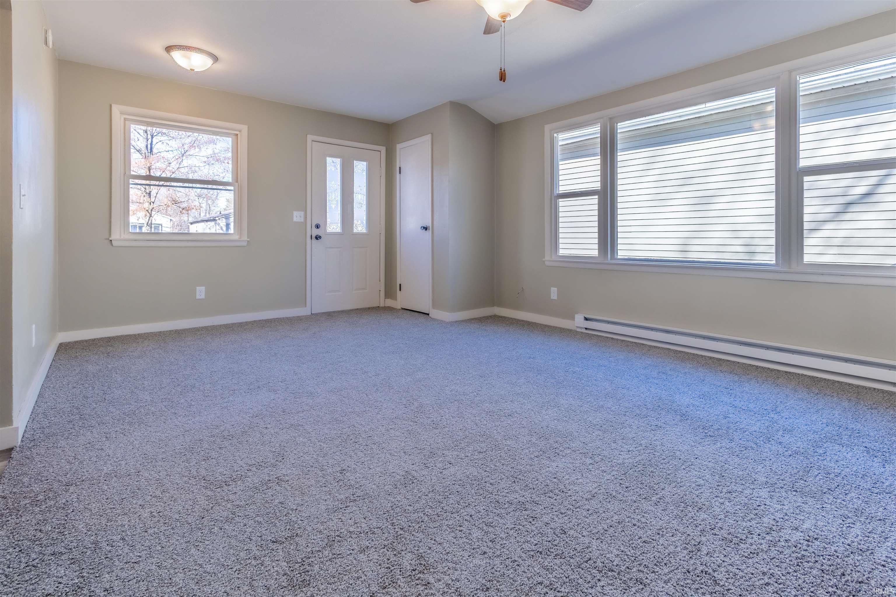 Entryway with ceiling fan, light colored carpet, and baseboard heating