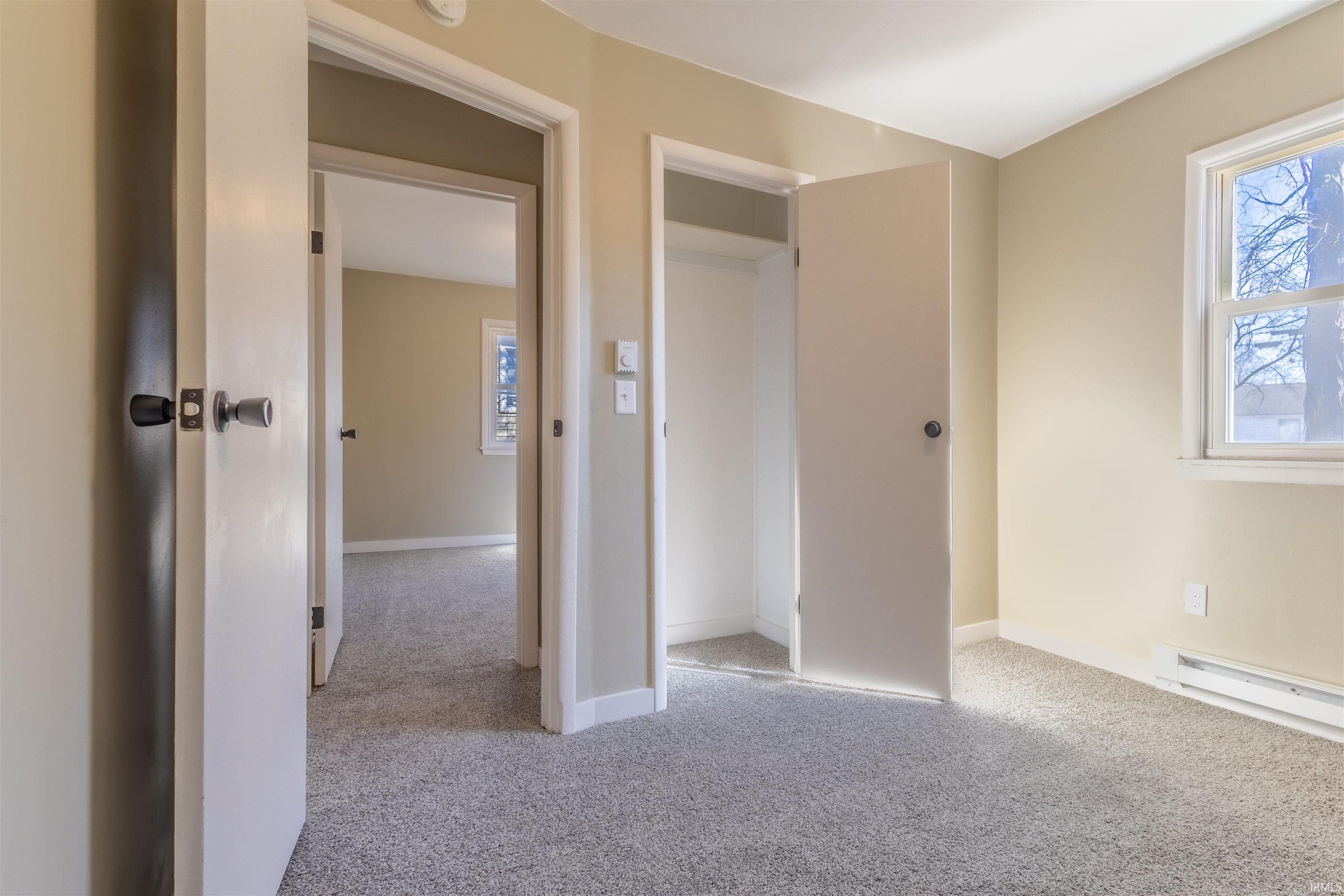 Unfurnished bedroom featuring light carpet and multiple windows
