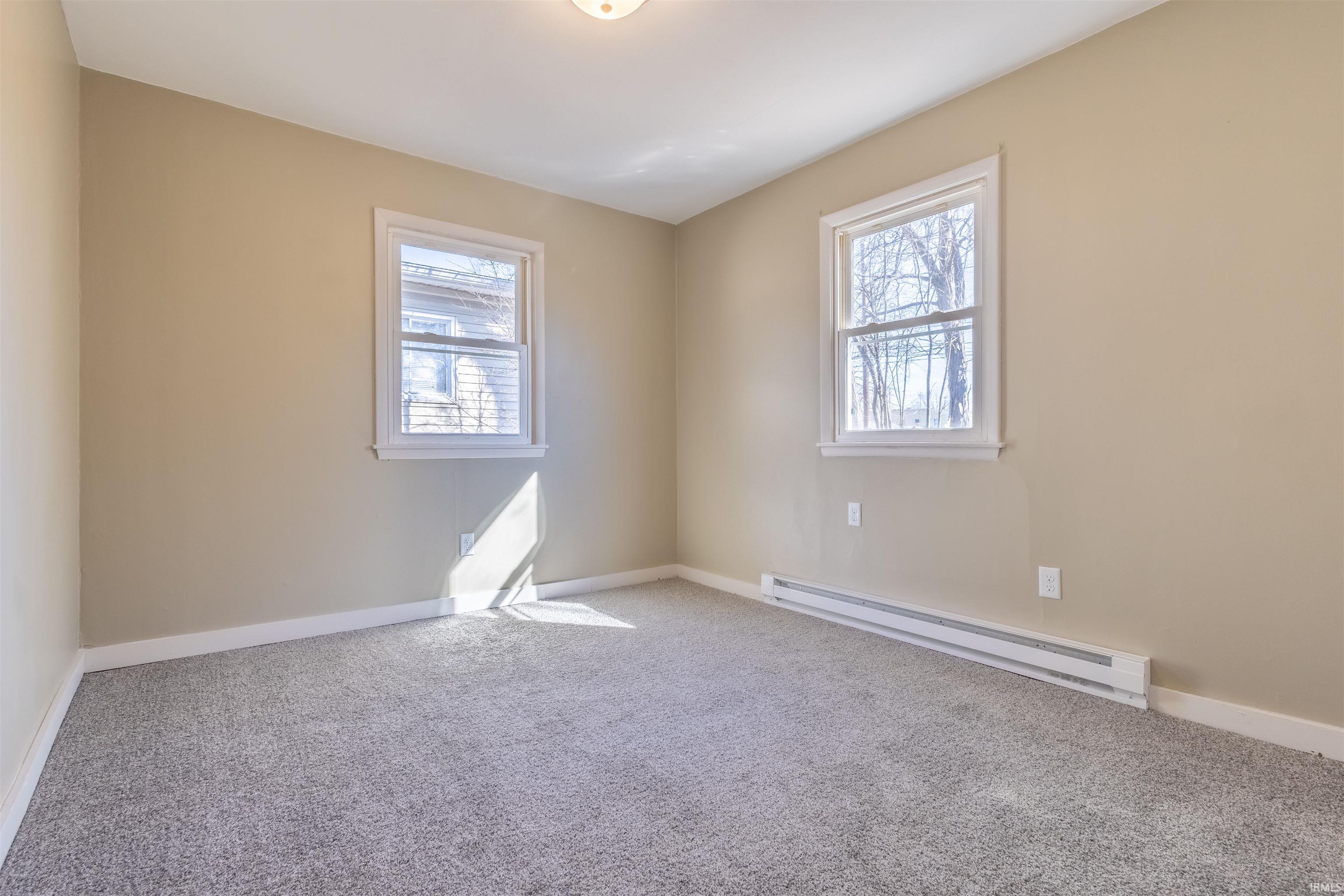 Carpeted empty room featuring a baseboard radiator and baseboards