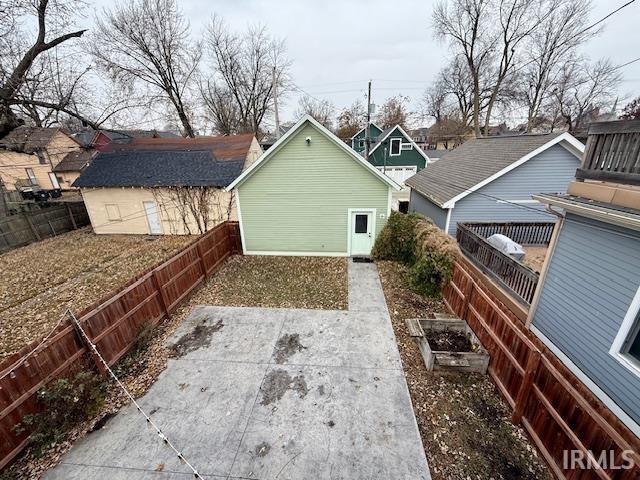 Rear view of home featuring stamped patio, raised  garden bed, and fenced backyard