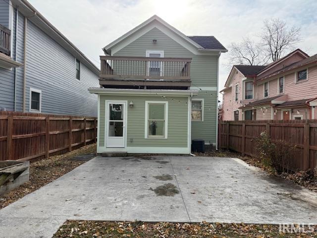 Rear view of property with a patio area, a fenced backyard, and a balcony