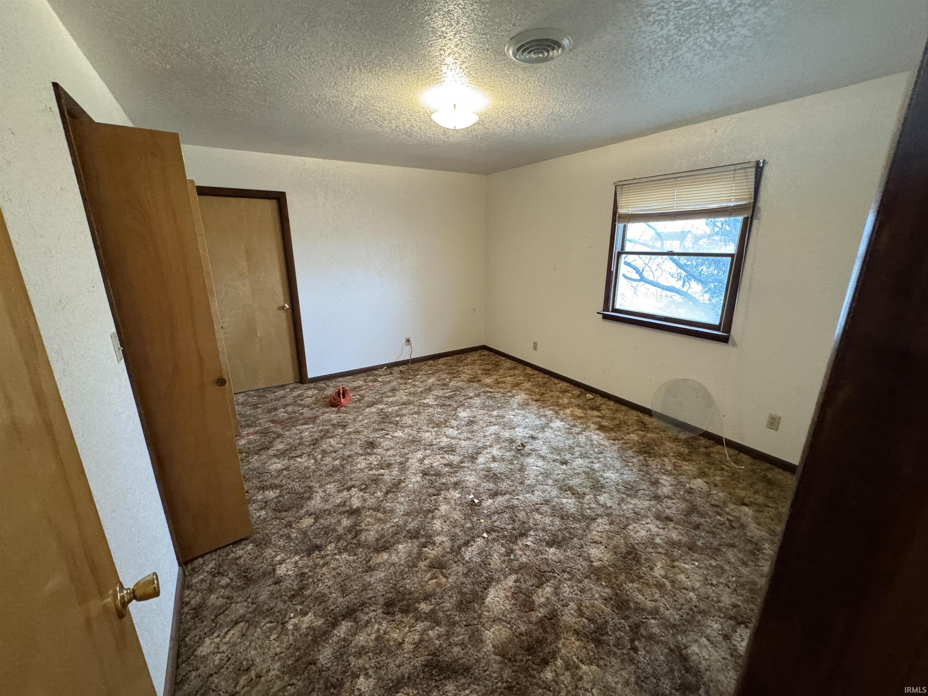 Unfurnished bedroom featuring a textured ceiling and carpet flooring