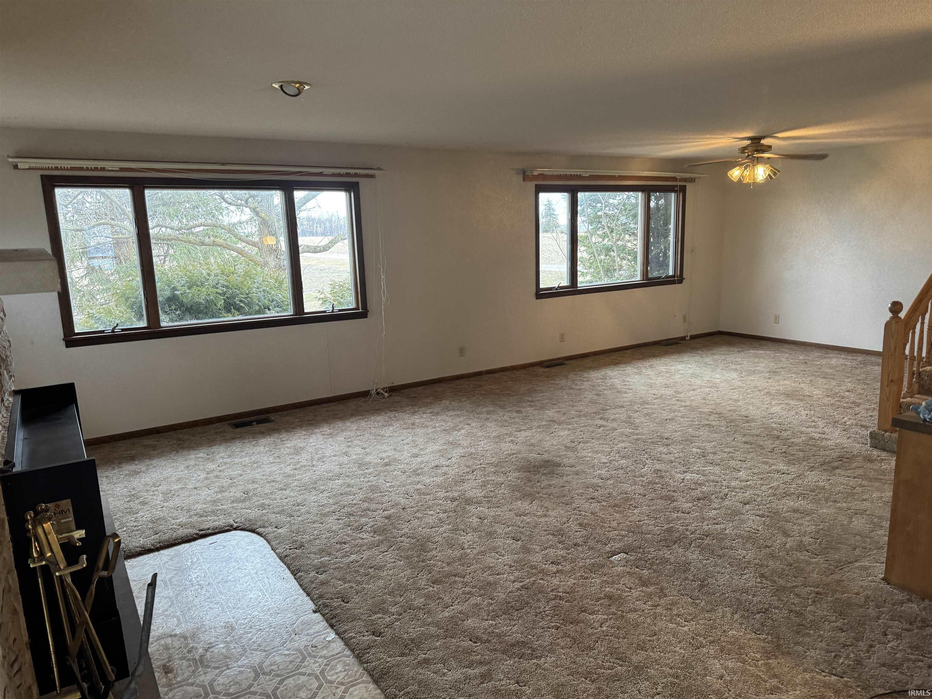 Unfurnished living room featuring a ceiling fan and carpet flooring