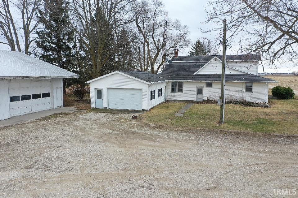 View of front of house with a garage, a chimney, driveway, and a front yard