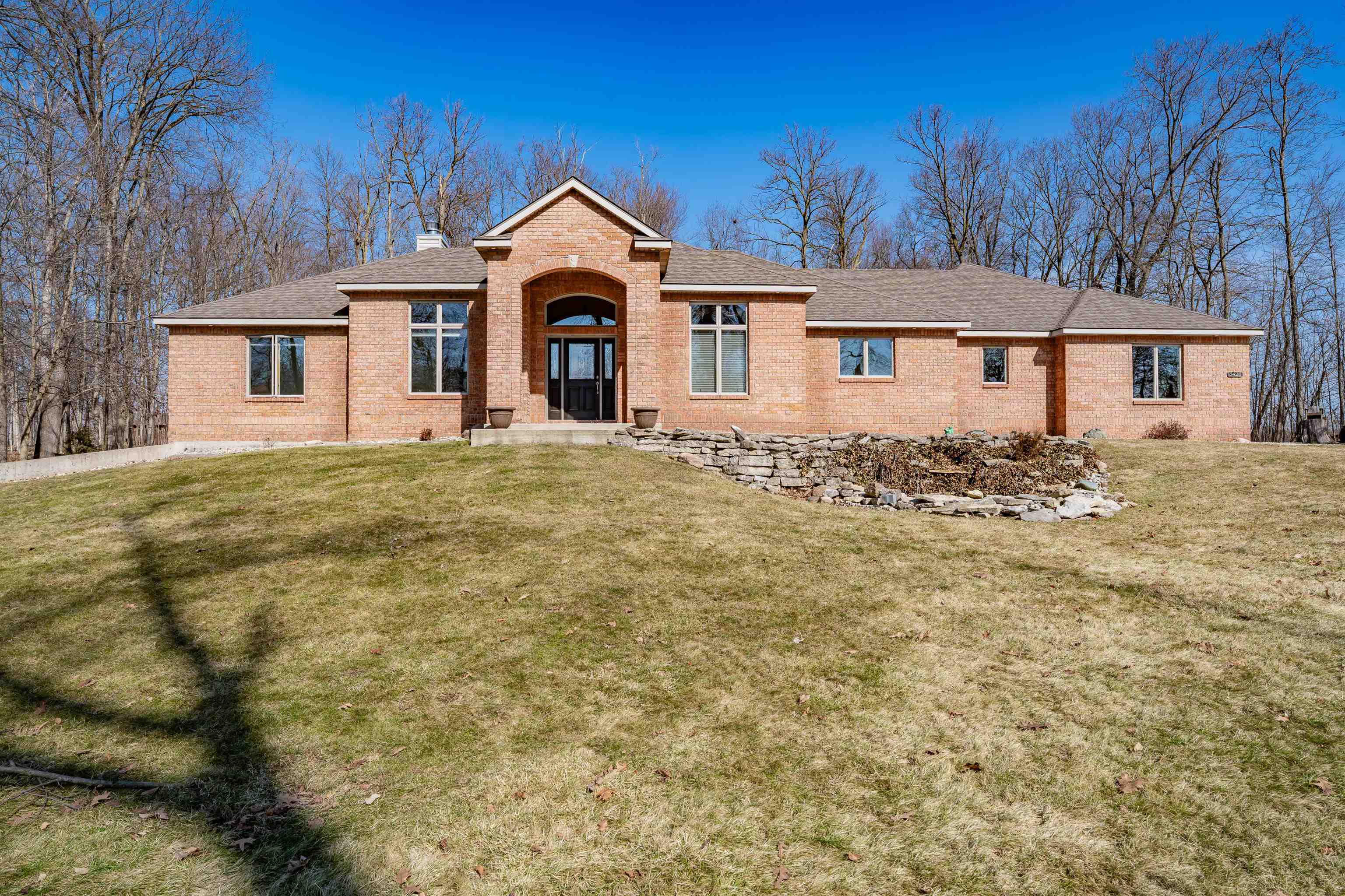 Ranch-style home featuring brick siding, a front lawn, a chimney, and a shingled roof