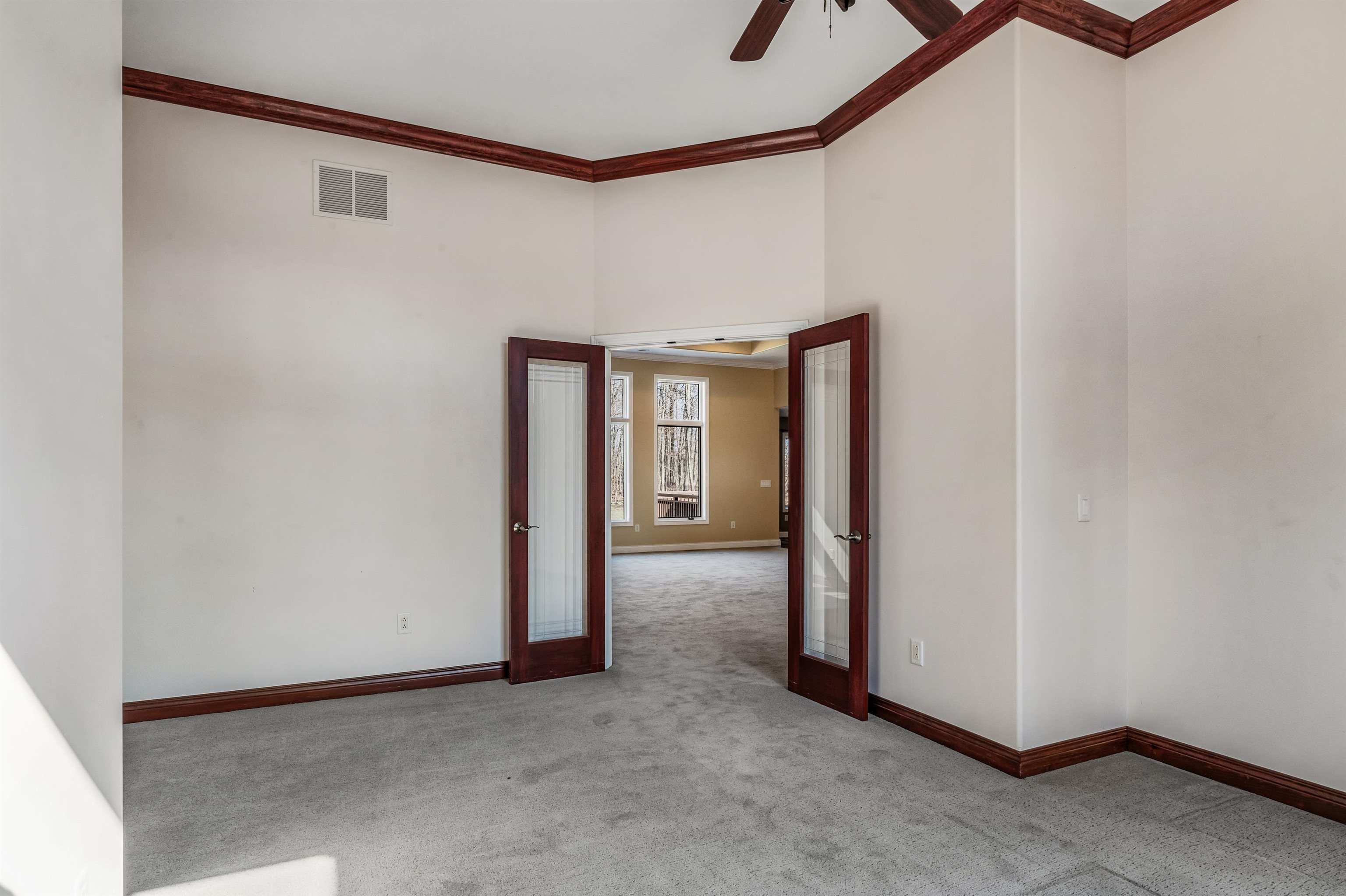 Spare room with ornamental molding, light carpet, ceiling fan, a high ceiling, and french doors