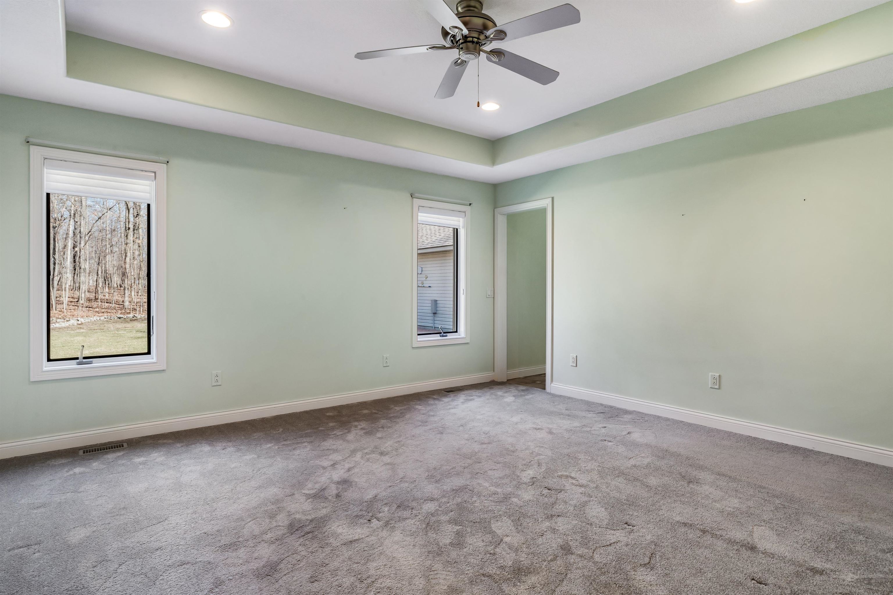 Carpeted empty room with ceiling fan, recessed lighting, and a raised ceiling