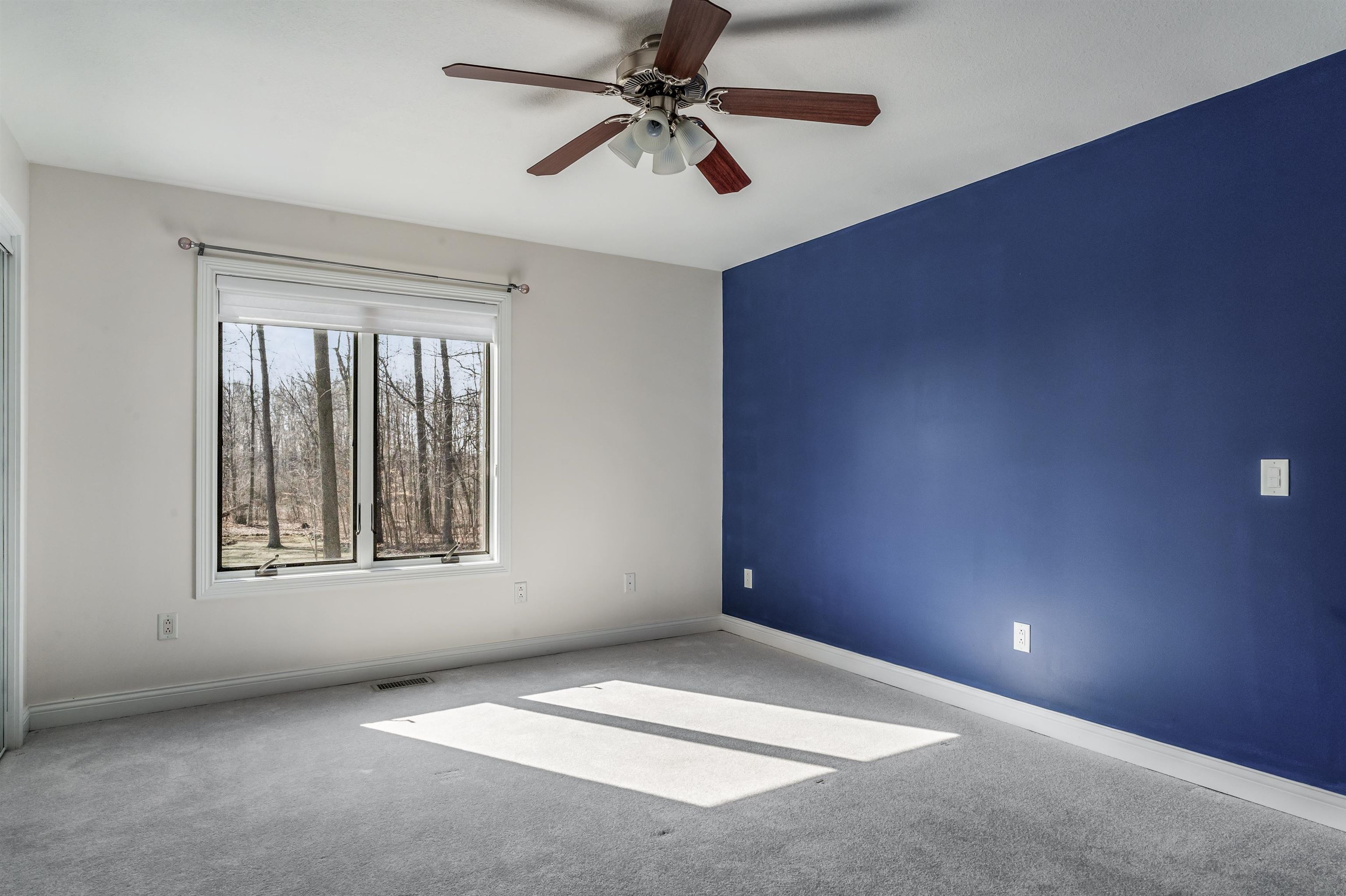Carpeted spare room featuring a ceiling fan and baseboards