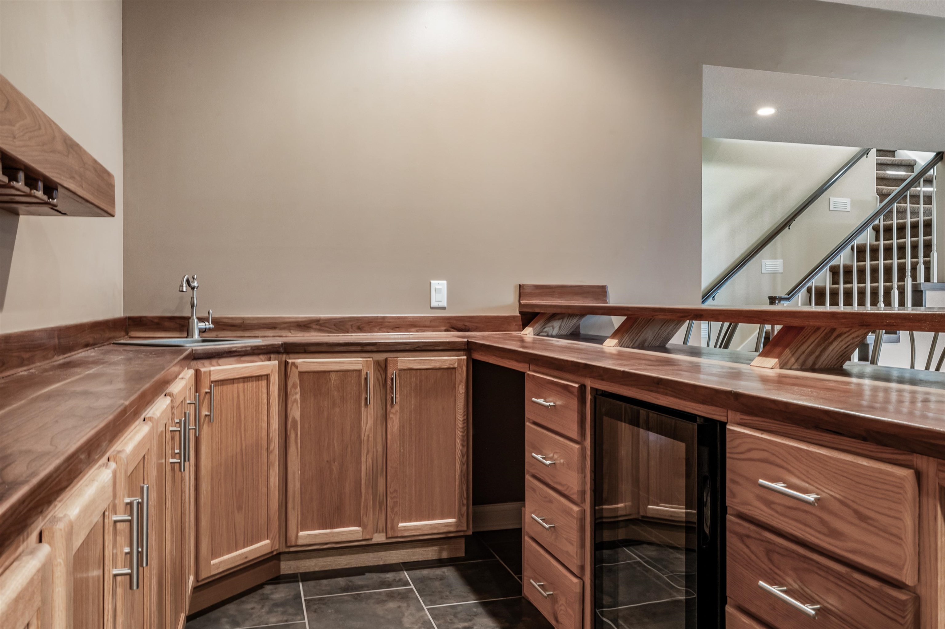 Kitchen featuring wood counters, beverage cooler, dark tile patterned flooring, and wood finish cabinets