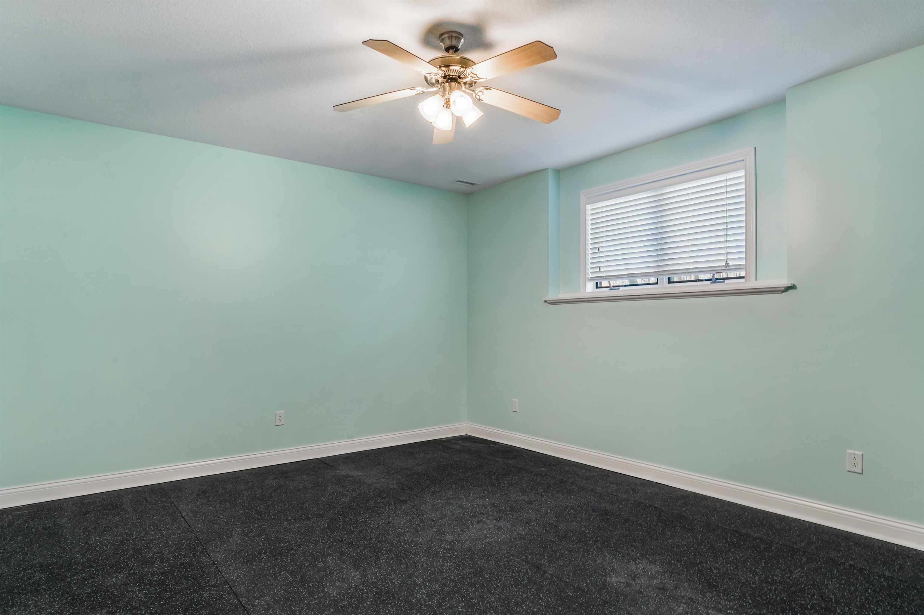 Empty room with a ceiling fan and dark colored carpet
